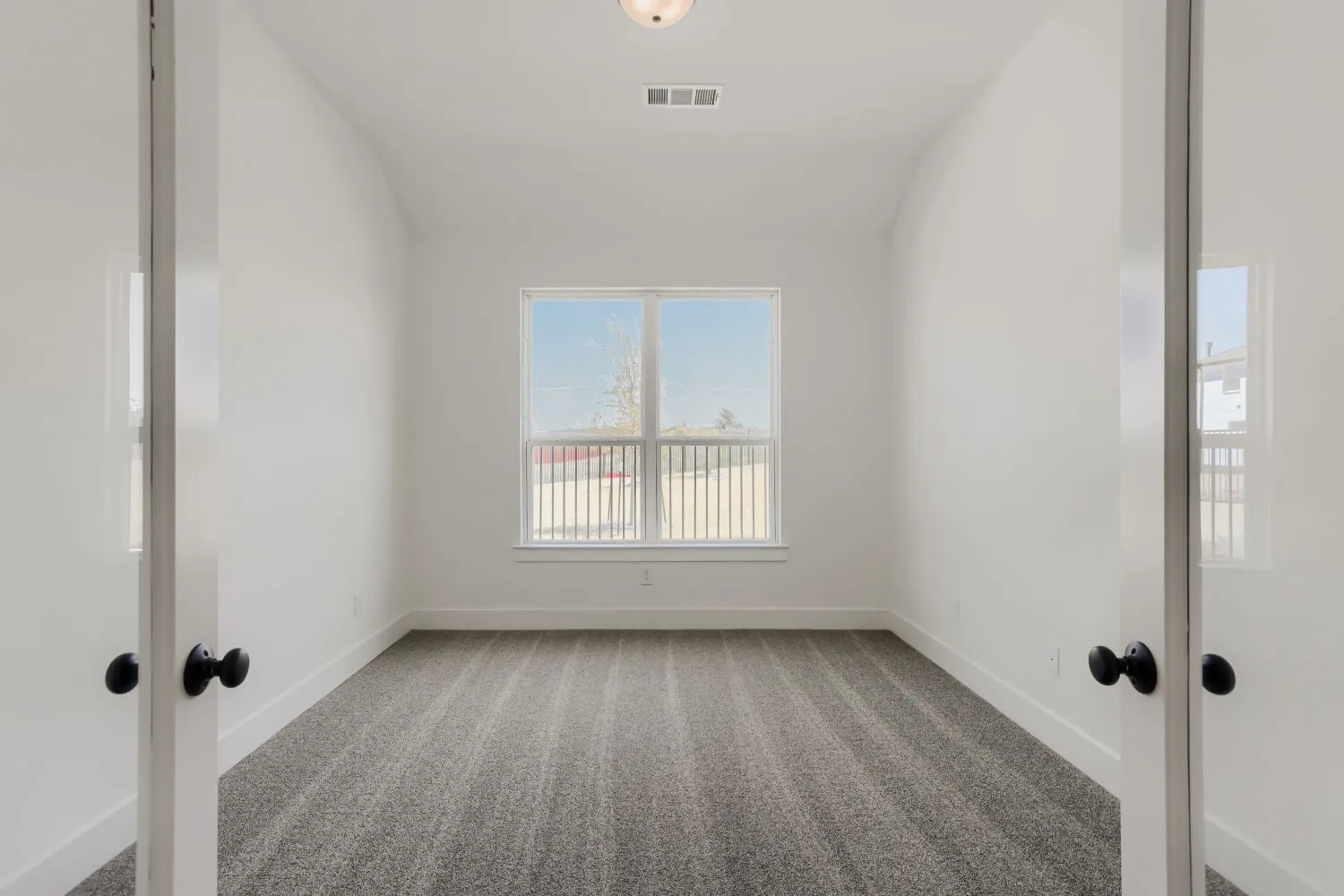 Bright interior with a window, white walls, and dark patterned carpeting