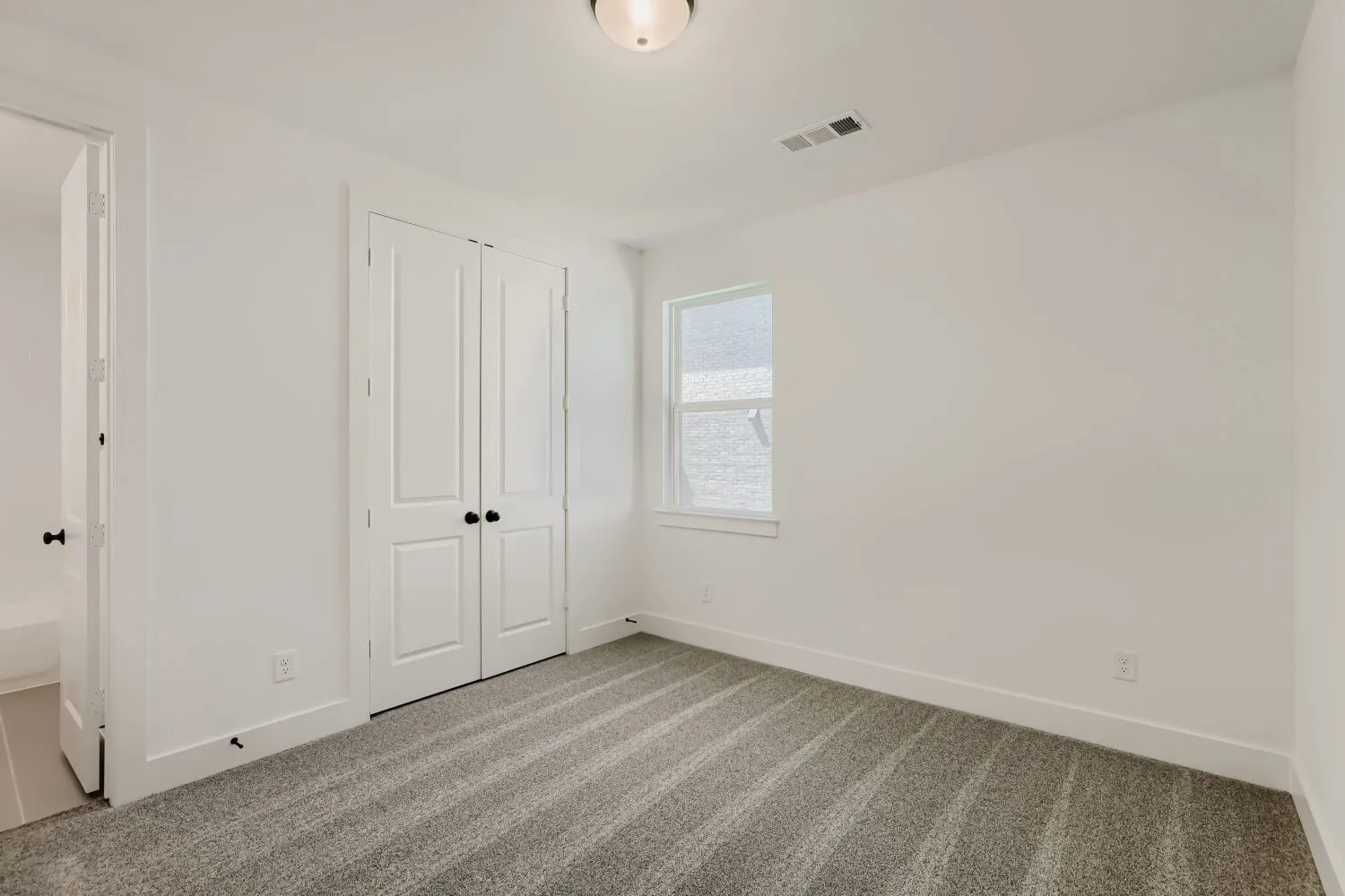 Recessed lighting, white walls, gray patterned carpet, double bi-fold closet doors, and a single window