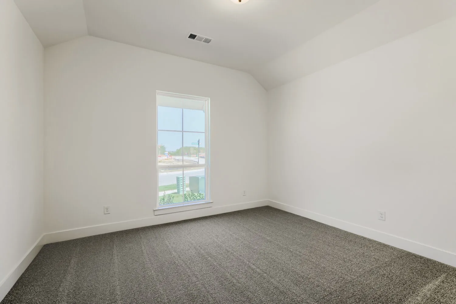Vaulted ceiling, bright white walls, dark gray carpet, white trim throughout, and a double-pane window