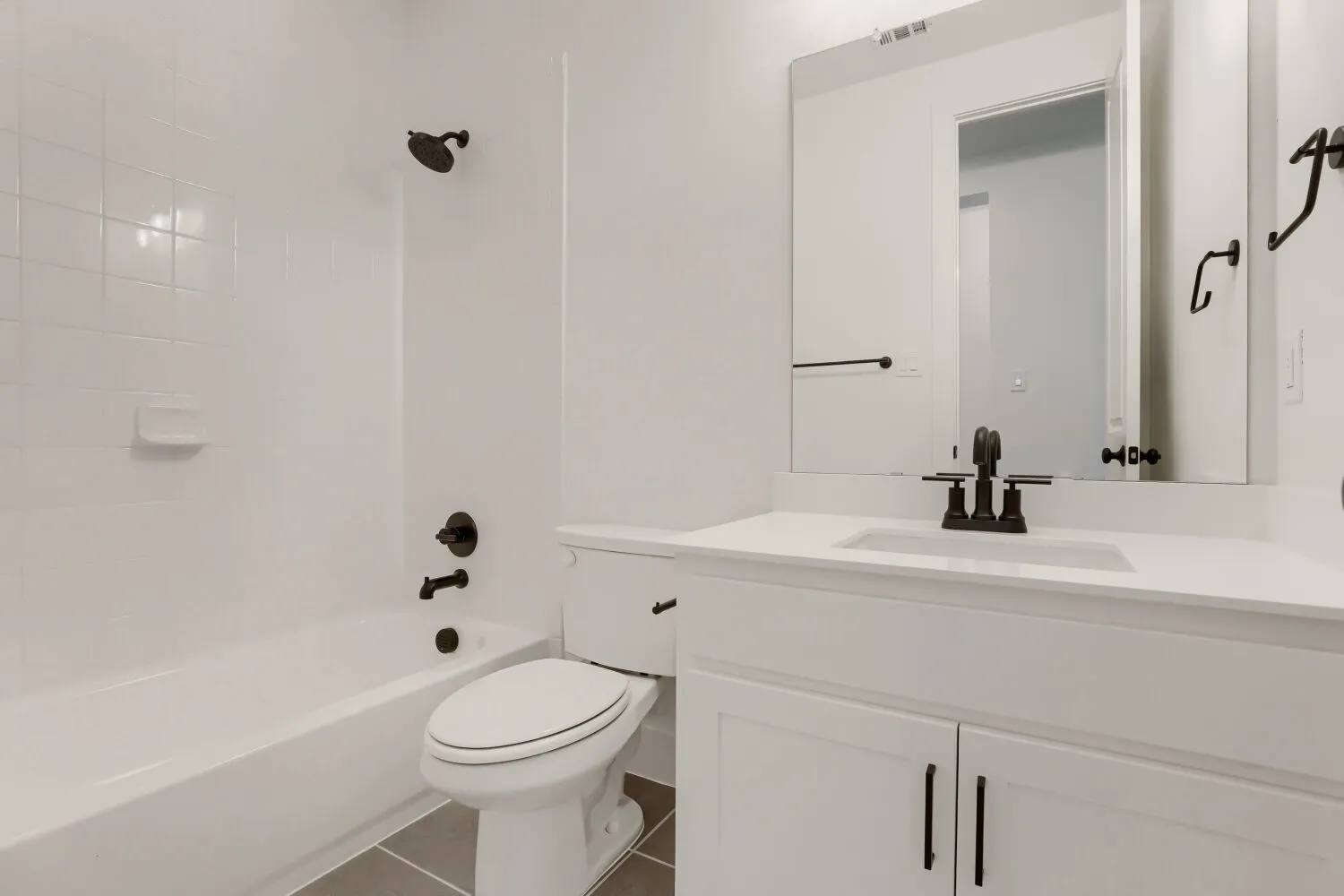 White vanity with shaker-style cabinetry, matte black hardware, integrated sink, and wall-mounted mirror