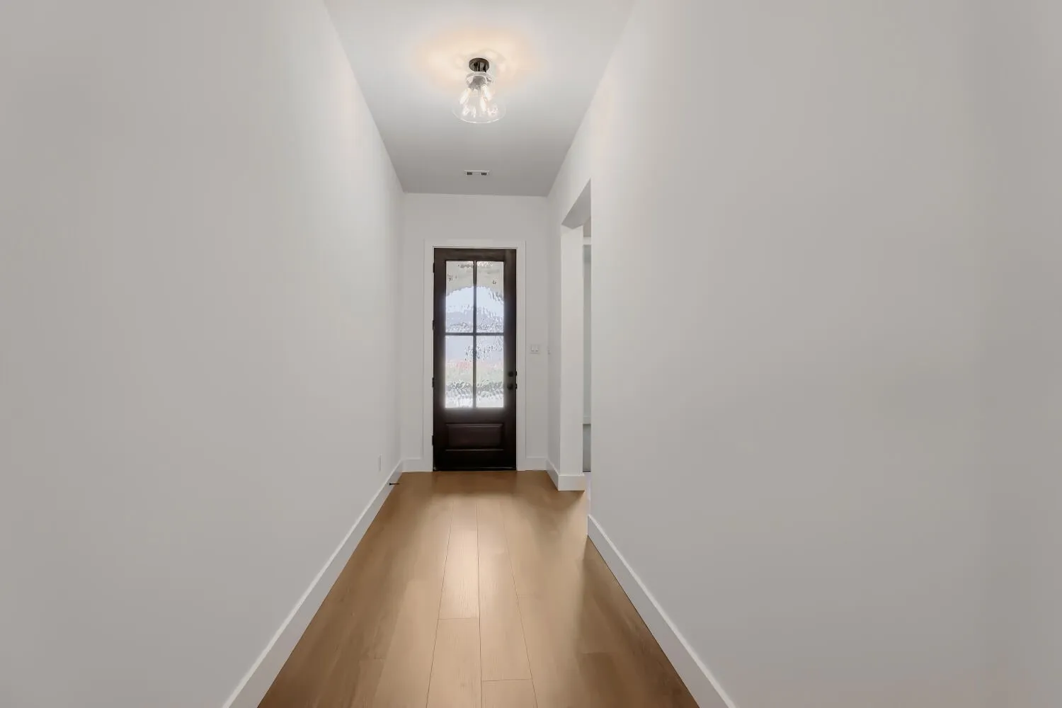 Hardwood-finish flooring, recessed lighting, and a dark wood entry door with glass panels