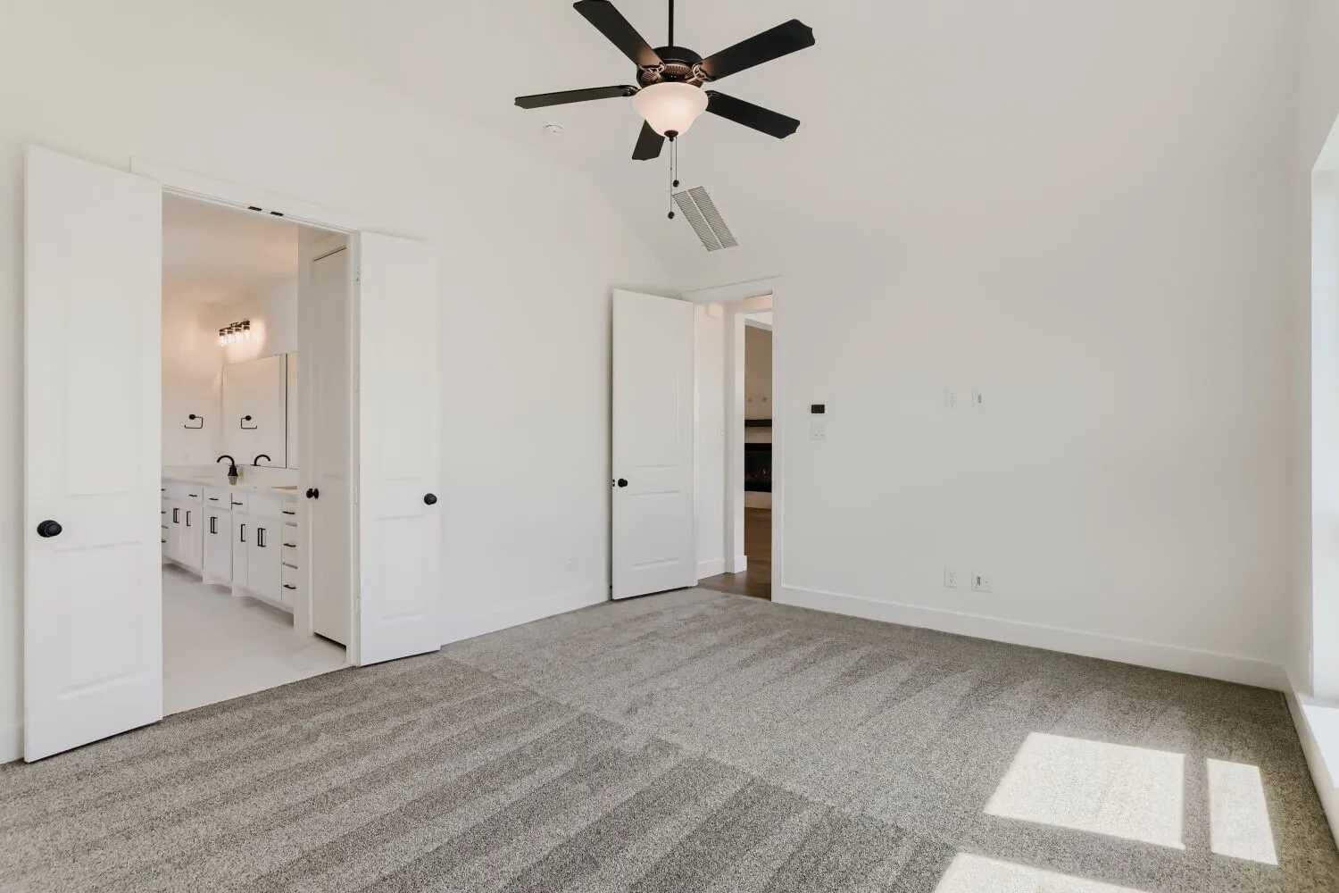 Vaulted ceiling, ceiling fan, carpet flooring, double doors, and white paneled doors