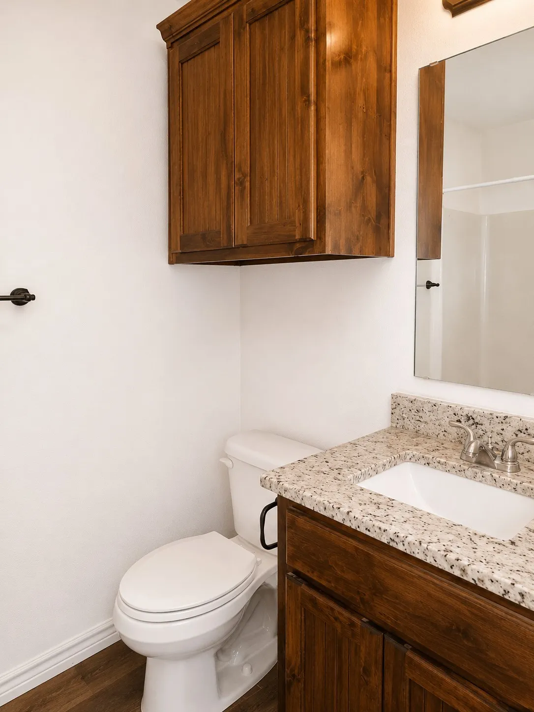 Bathroom featuring a wood-finish vanity with a light-toned granite countertop and an integrated sink