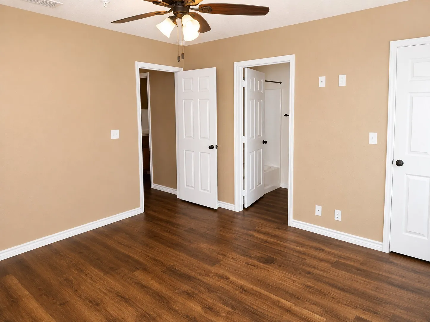 Spacious room featuring wood-finish flooring, neutral-toned walls, and white baseboards
