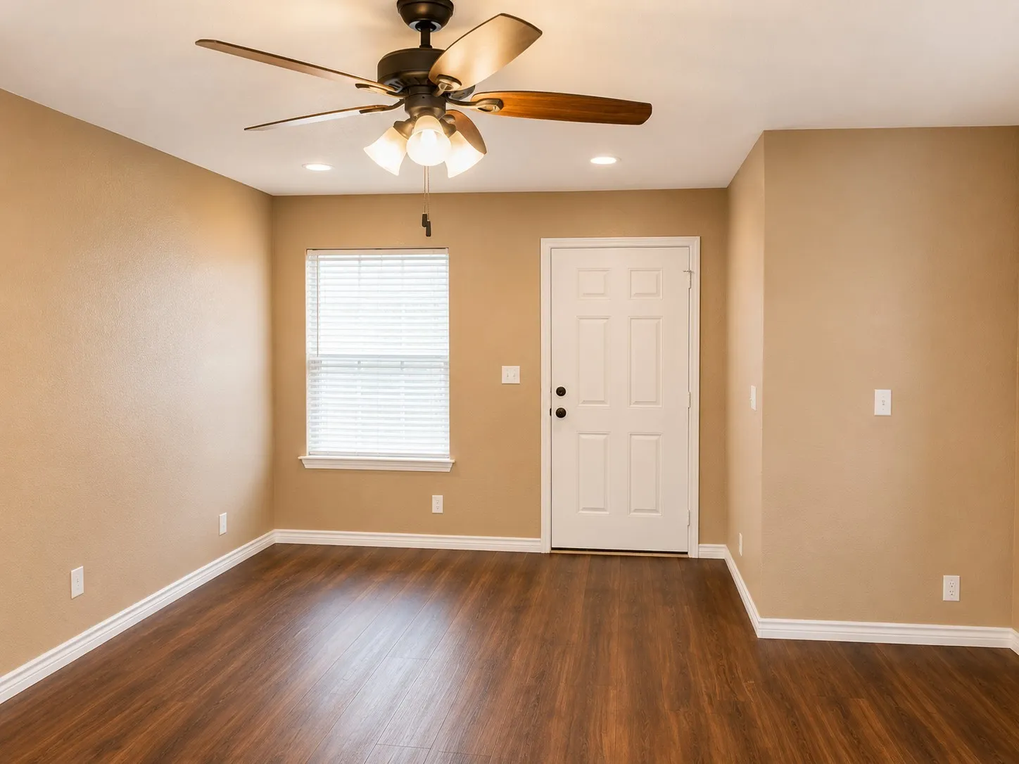 Open living area featuring wood-finish flooring, neutral wall tones, white trim, and a ceiling fan with integrated lighting