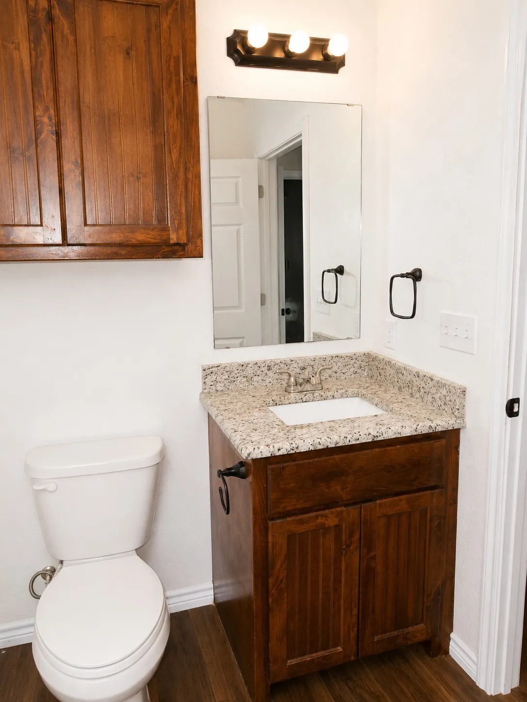 Bathroom featuring a wood-finish vanity with an integrated sink and granite-style countertop