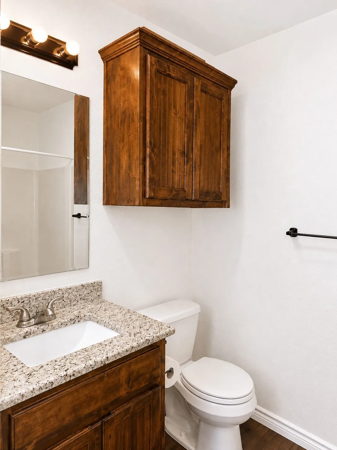 Bathroom featuring a wood-finish vanity with a granite-style countertop, undermount sink, and brushed nickel faucet
