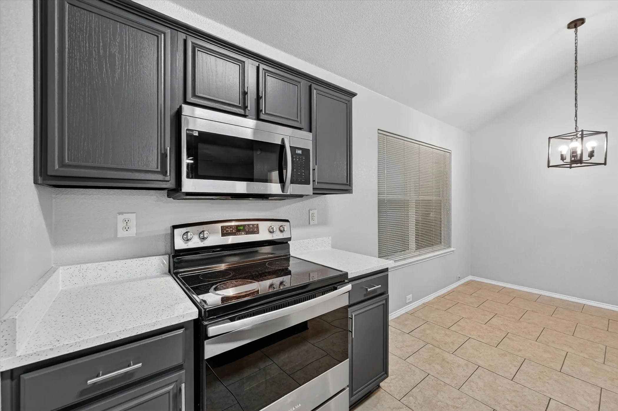 Kitchen featuring dark cabinetry, speckled countertops, and stainless steel appliances
