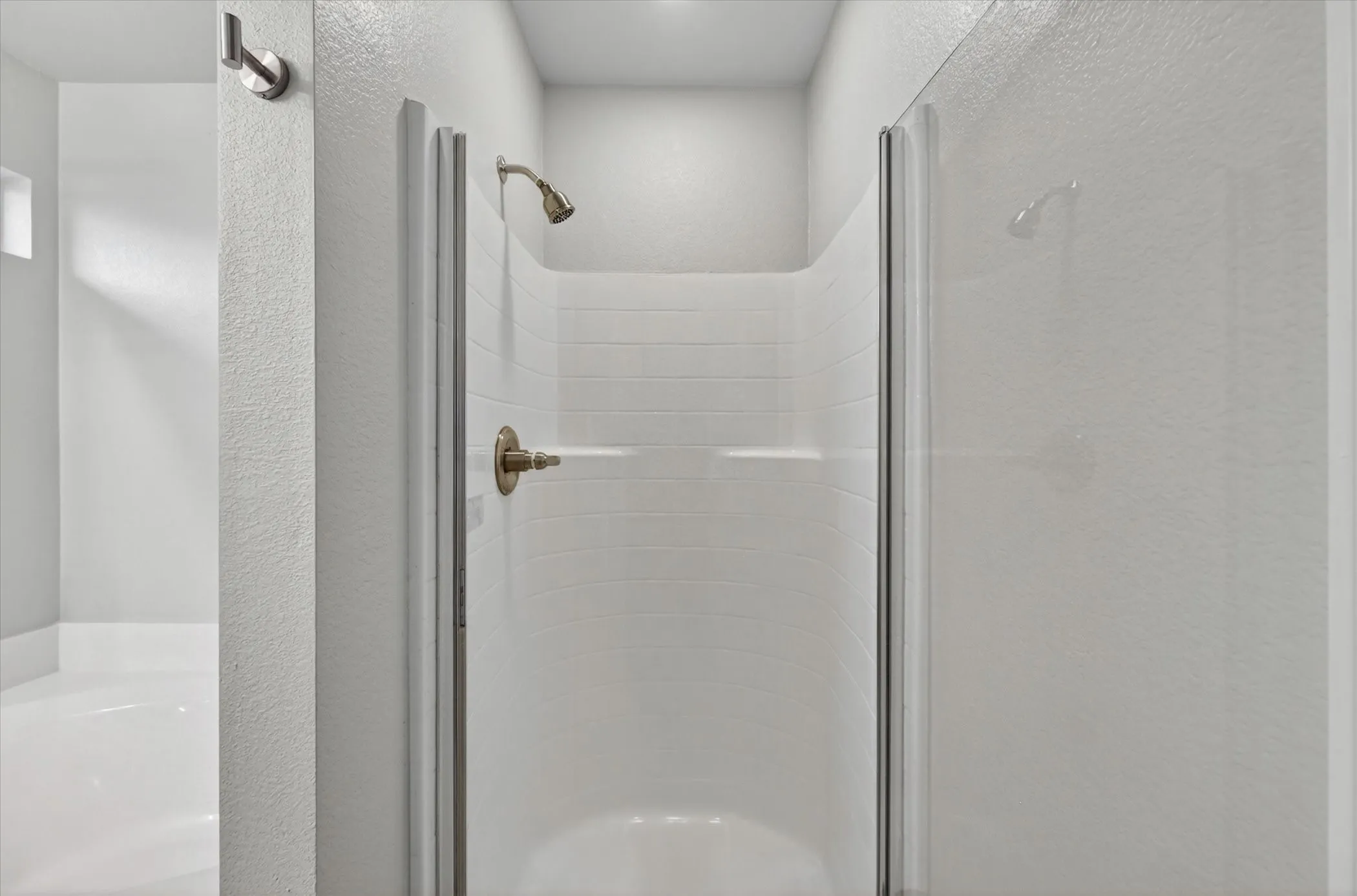 Standalone shower with clear glass enclosure and bronze fixtures