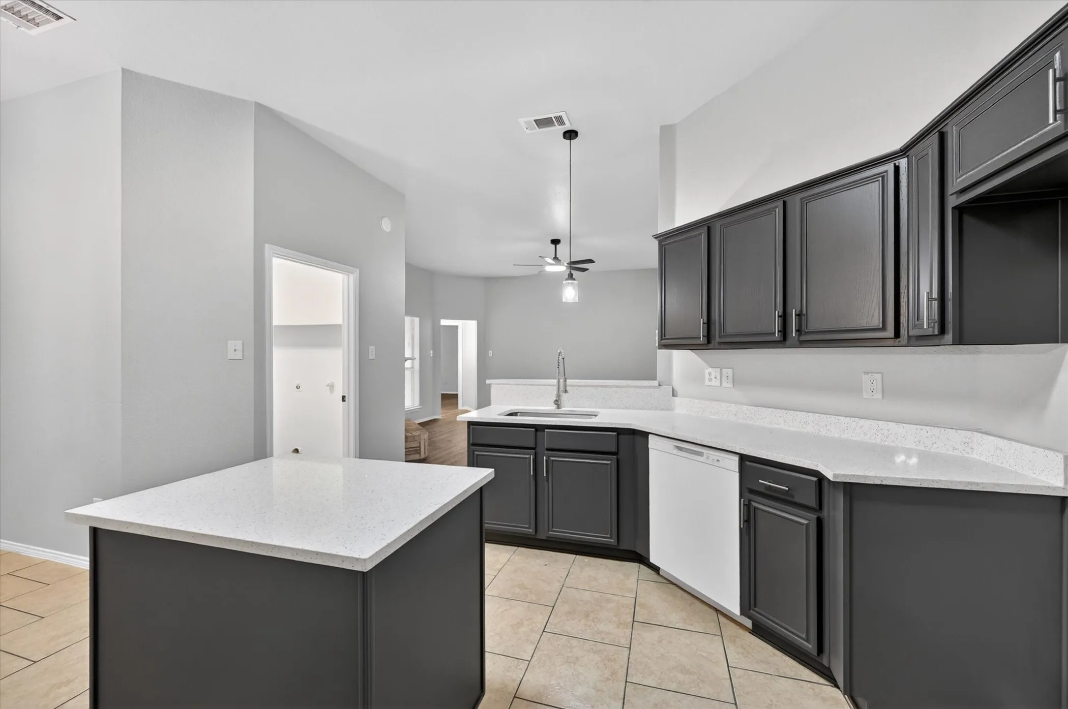 Kitchen featuring dark cabinetry, white speckled countertops, an undermount sink with a gooseneck faucet, a built-in dishwasher, and tile flooring