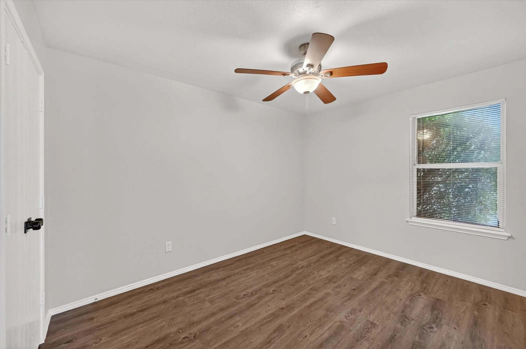 Interior room featuring wood-finish flooring, light gray walls, and white baseboards