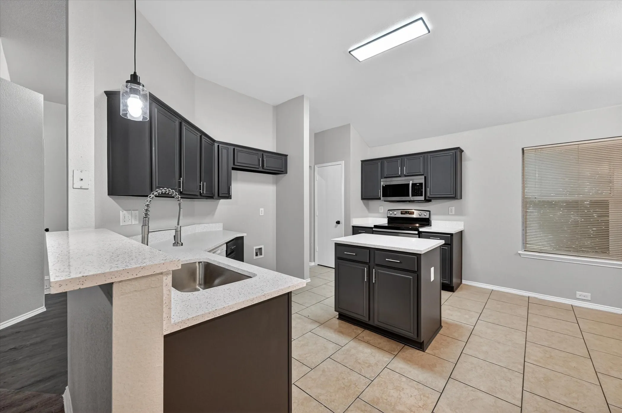 Kitchen featuring dark cabinetry, light countertops, and a central island