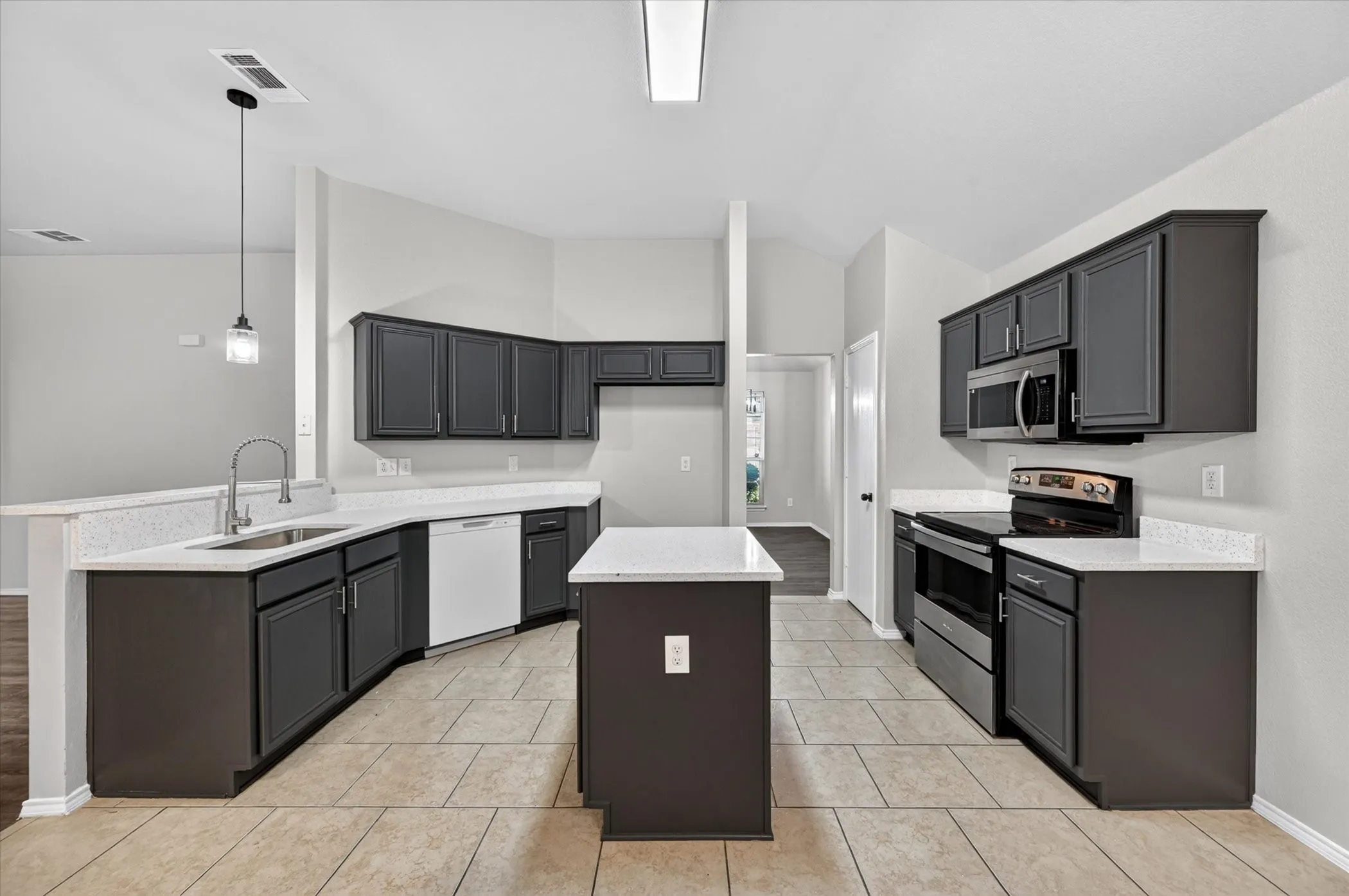 Kitchen featuring dark cabinetry, light countertops, stainless steel appliances, a central island, and tile flooring