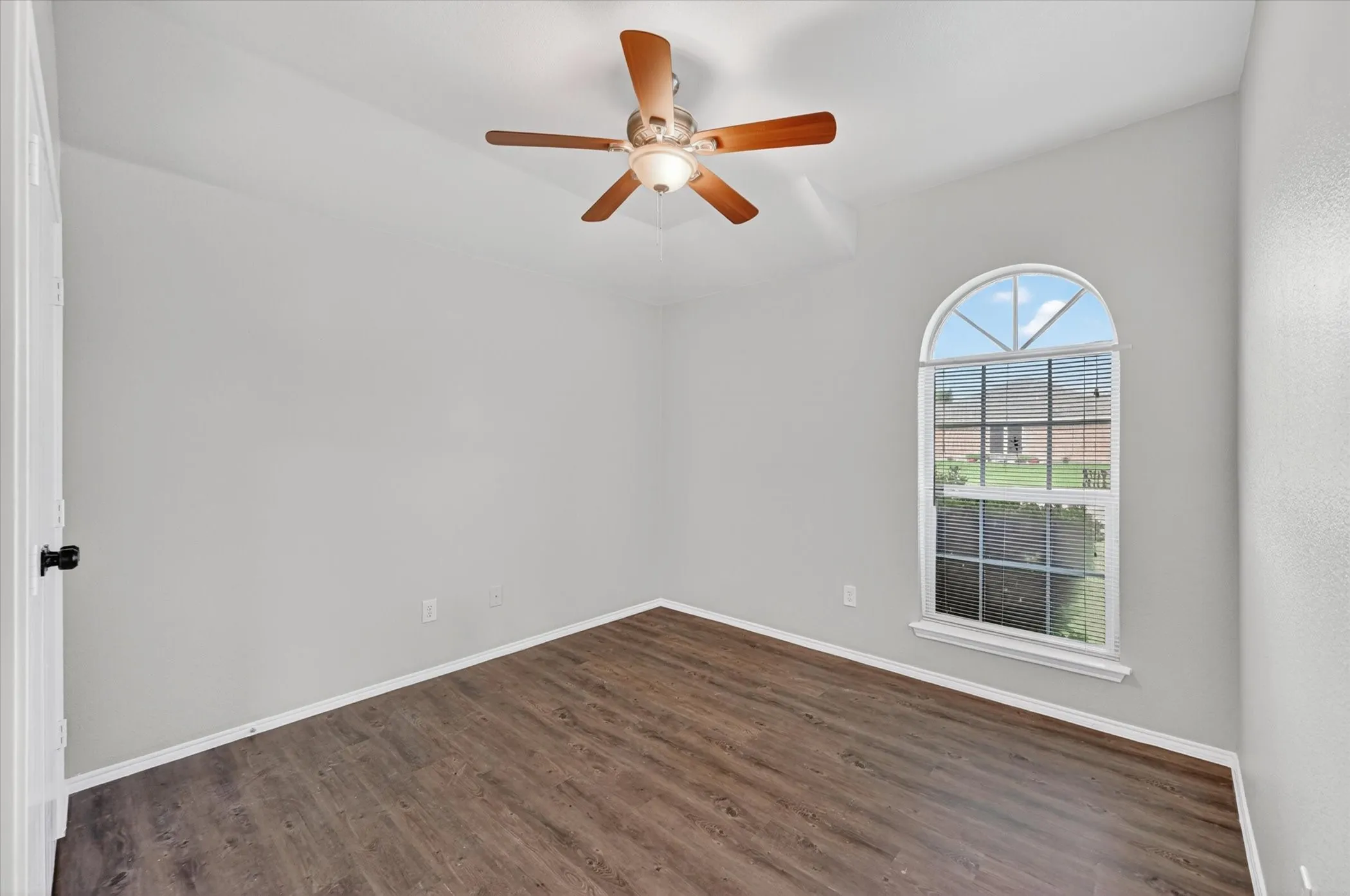 Bedroom featuring wood-finish flooring, light grey walls, and a vaulted ceiling with a ceiling fan