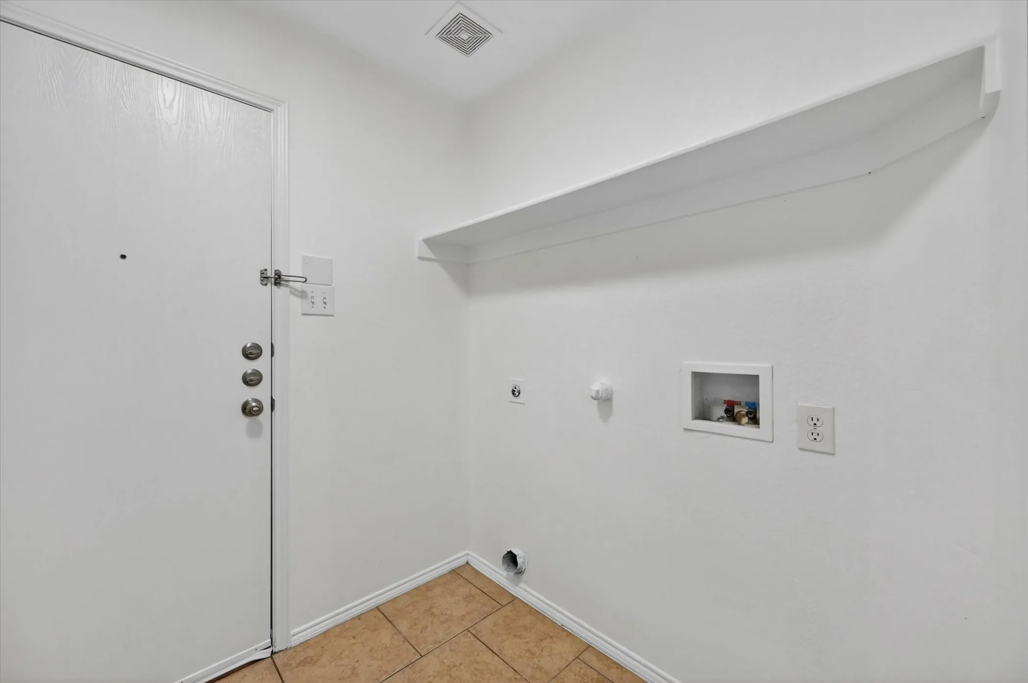 Dedicated utility space featuring tile flooring and a white built-in shelf
