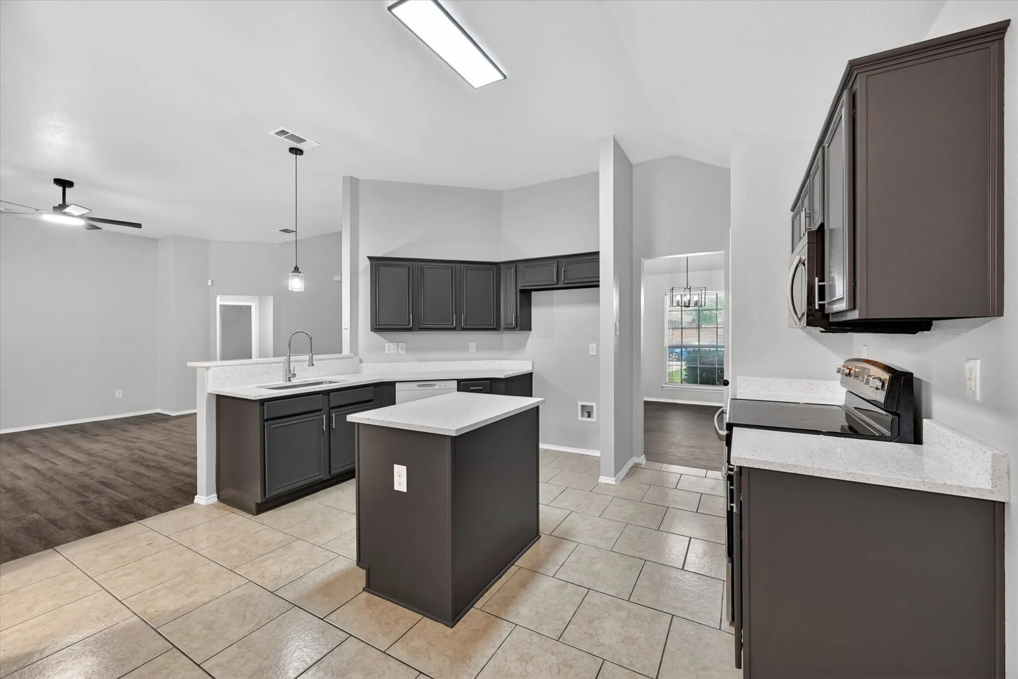 Modern kitchen featuring dark cabinetry, light-toned countertops, and a central island