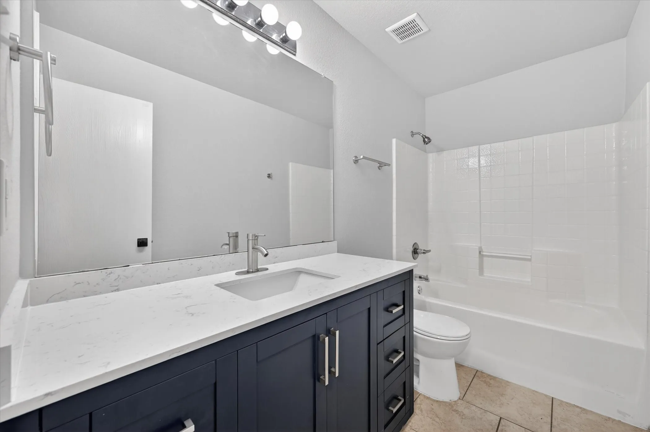 Vanity featuring a white countertop with an undermount sink, brushed nickel faucet, and dark wood-finish cabinetry with drawers and doors