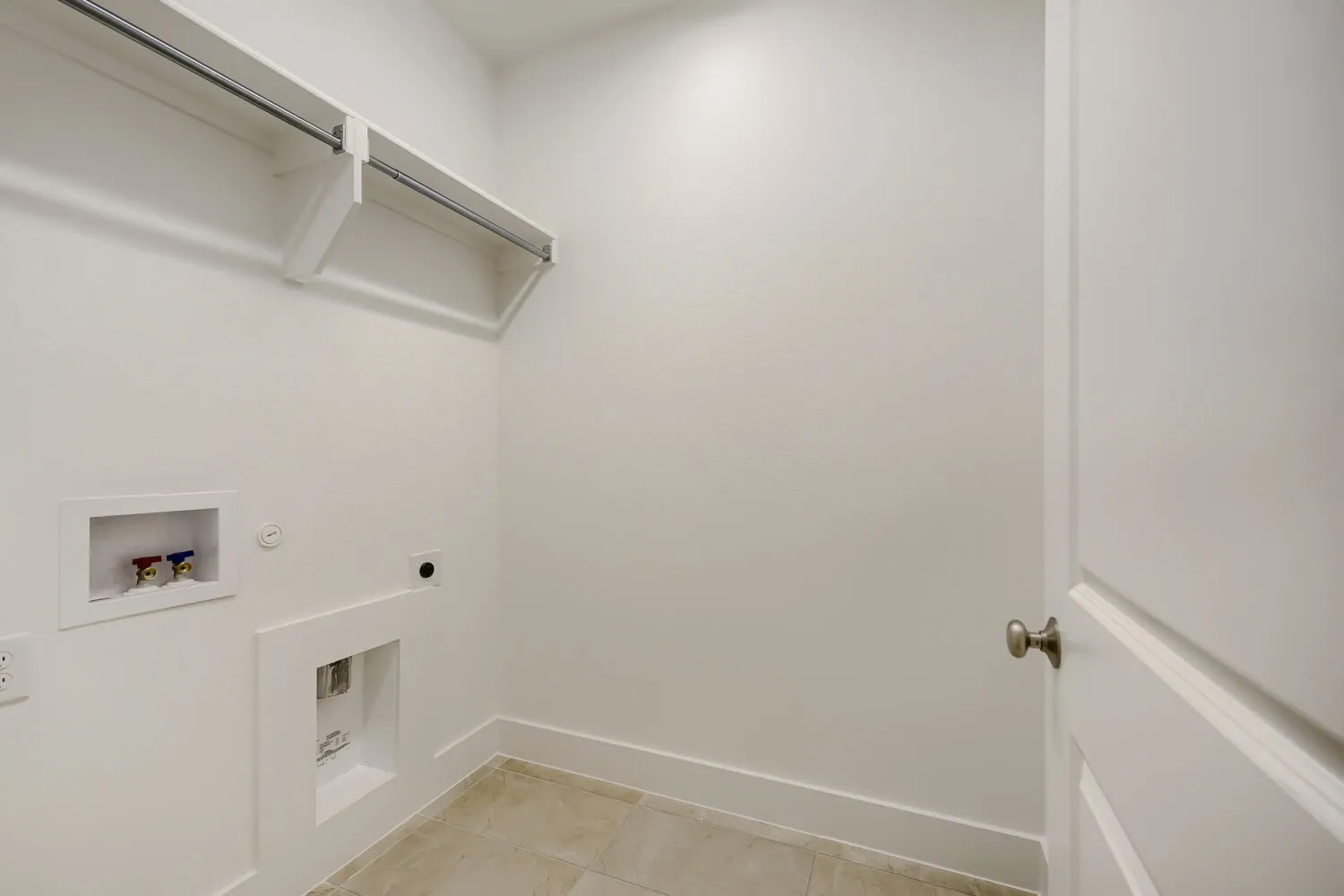 Laundry area featuring tiled flooring, white baseboards, and bright white walls