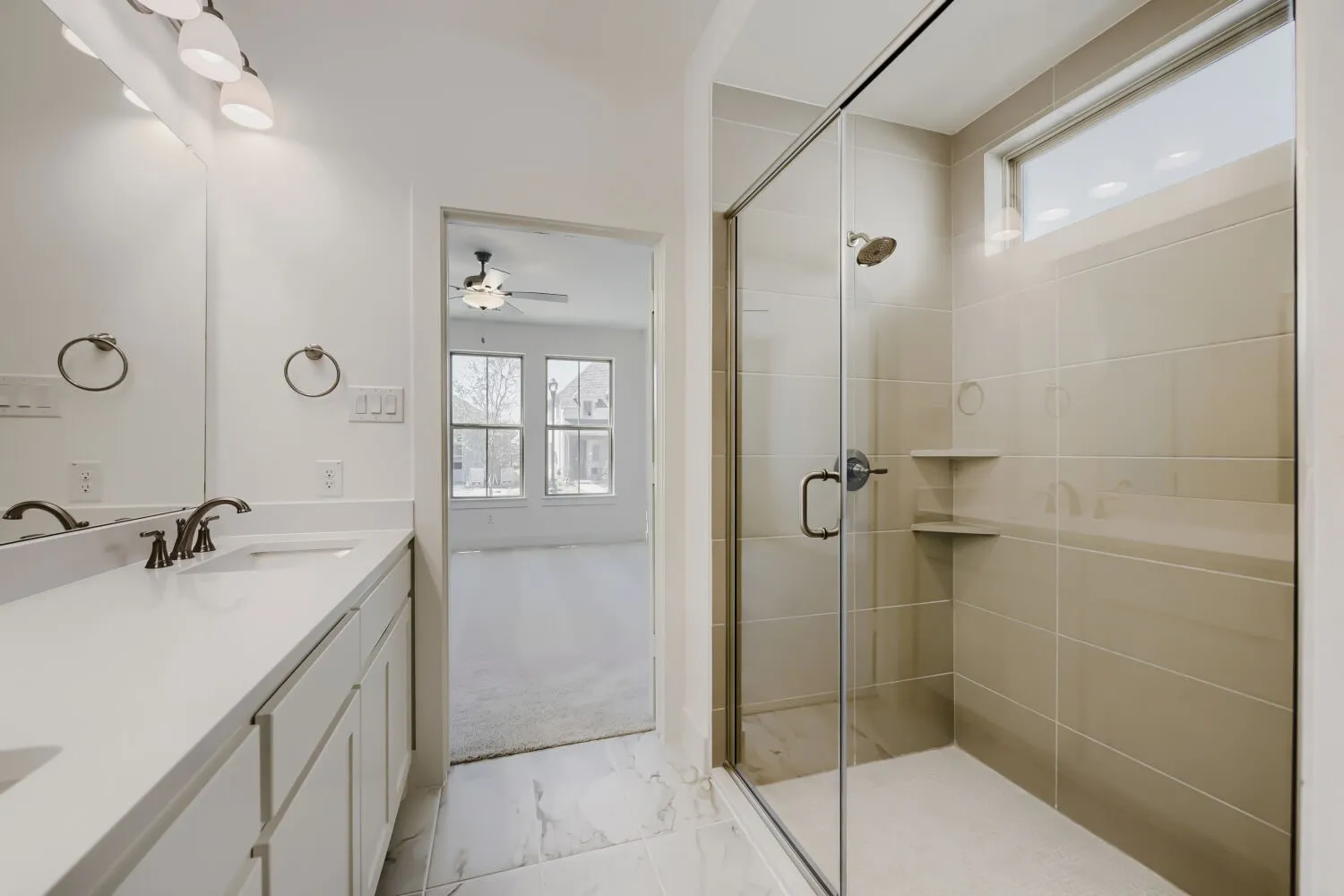 Dual vanity with white countertops and dark bronze fixtures, framed mirror, and three-light vanity bar