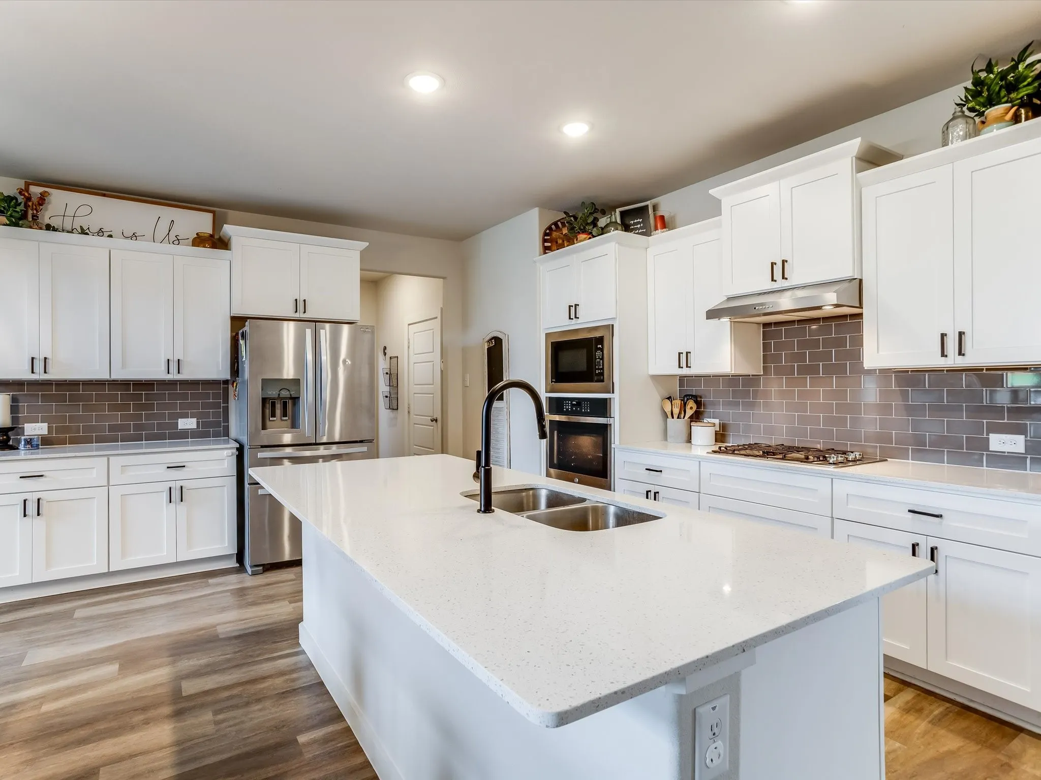 Modern kitchen featuring a large central island with a double basin sink and gooseneck faucet