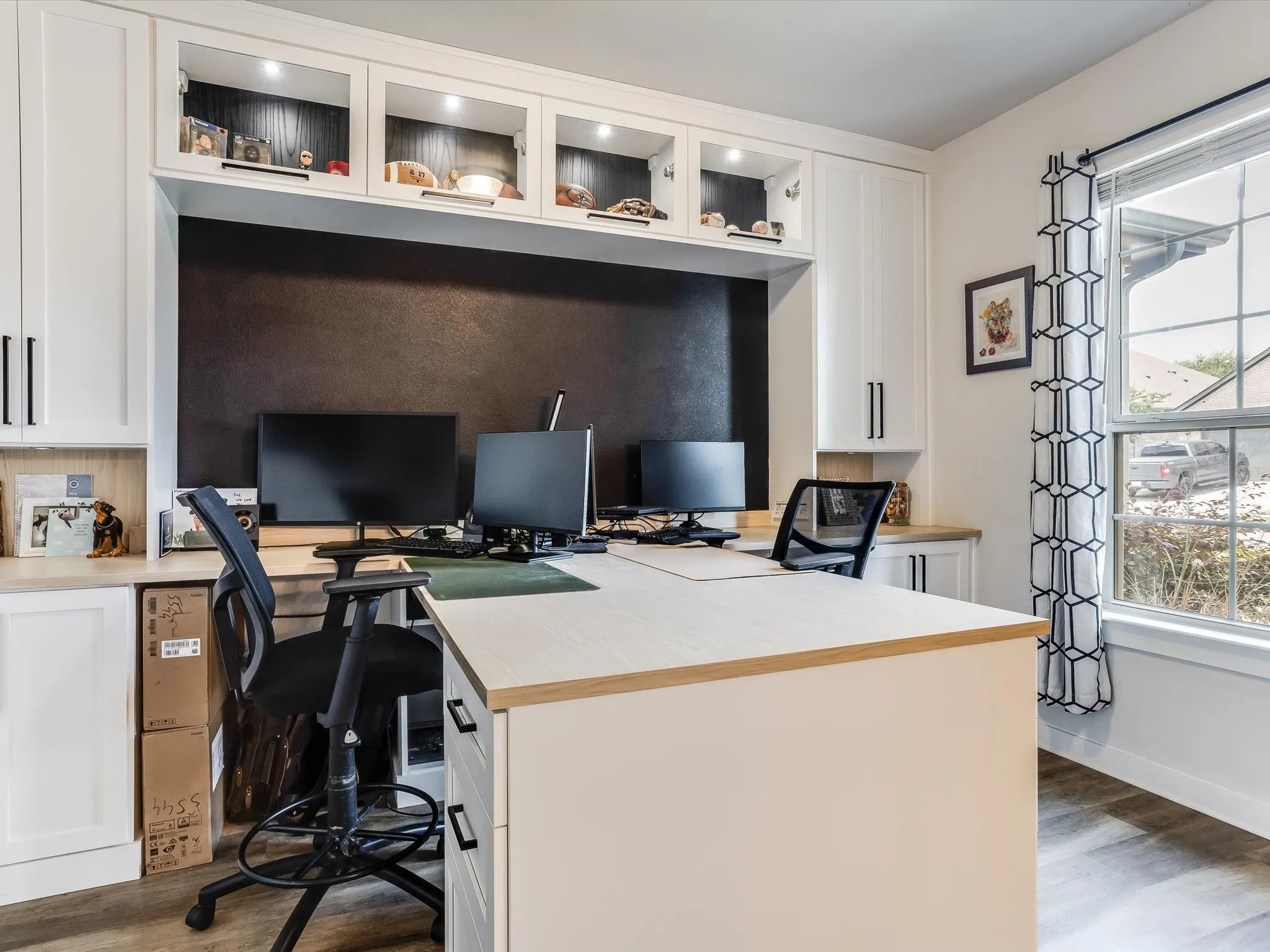 Dedicated workspace featuring white built-in cabinetry, a dark accent wall, and wood-finish flooring