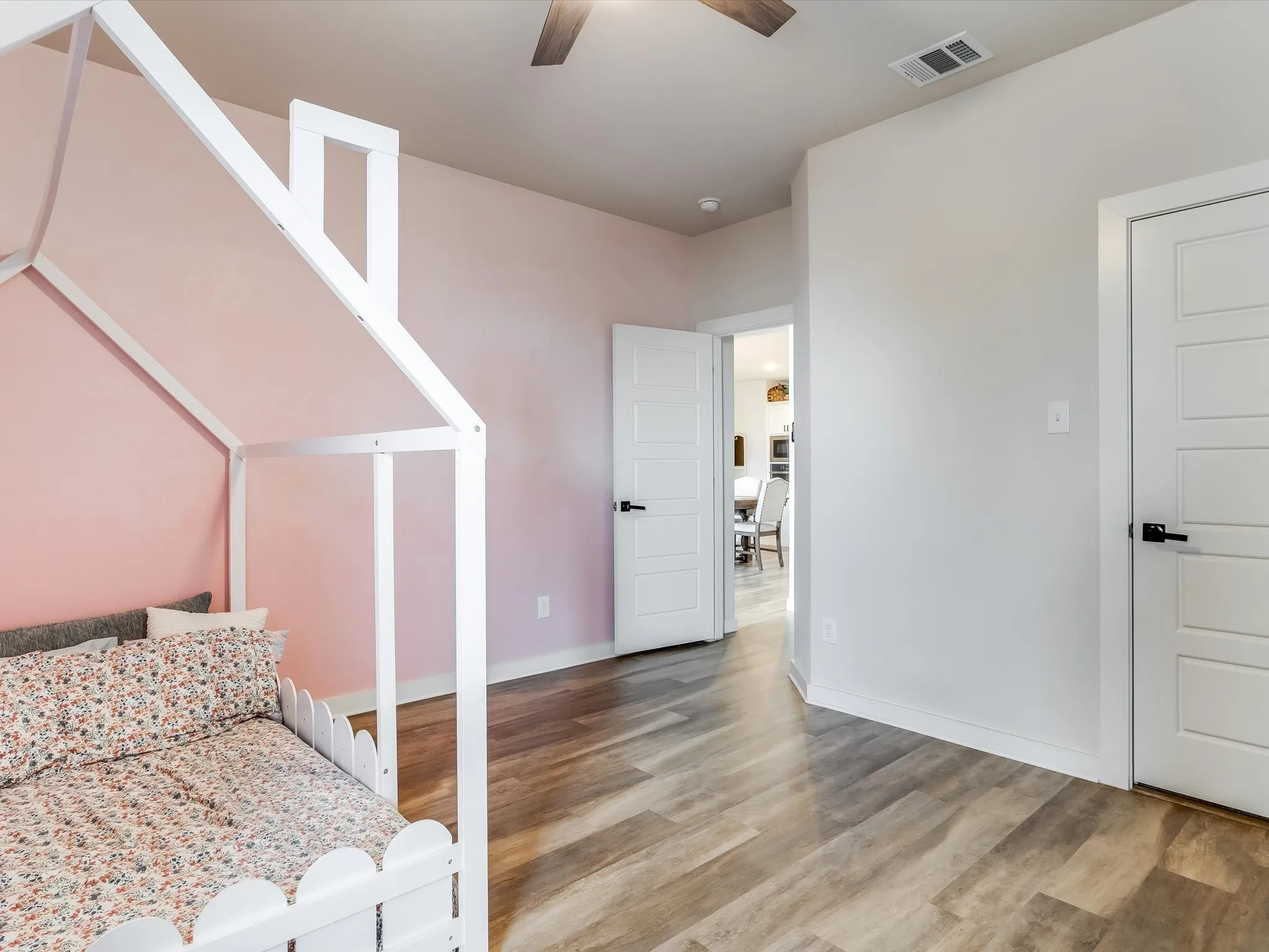 Spacious room featuring wood-finish flooring, a contemporary ceiling fan, and painted walls