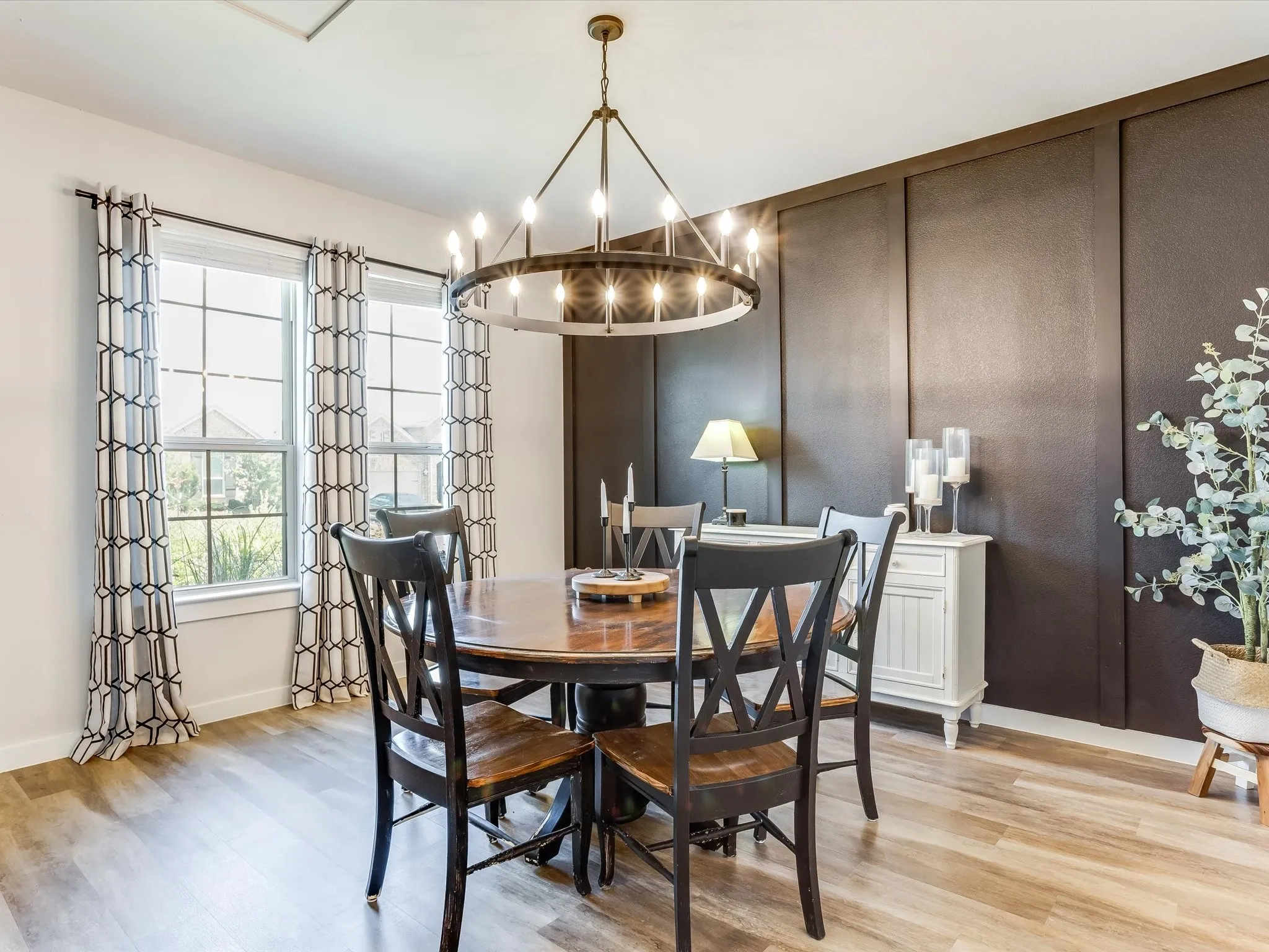 Formal dining space featuring wood-finish flooring, a contemporary chandelier, two large windows, a paneled accent wall, and recessed lighting