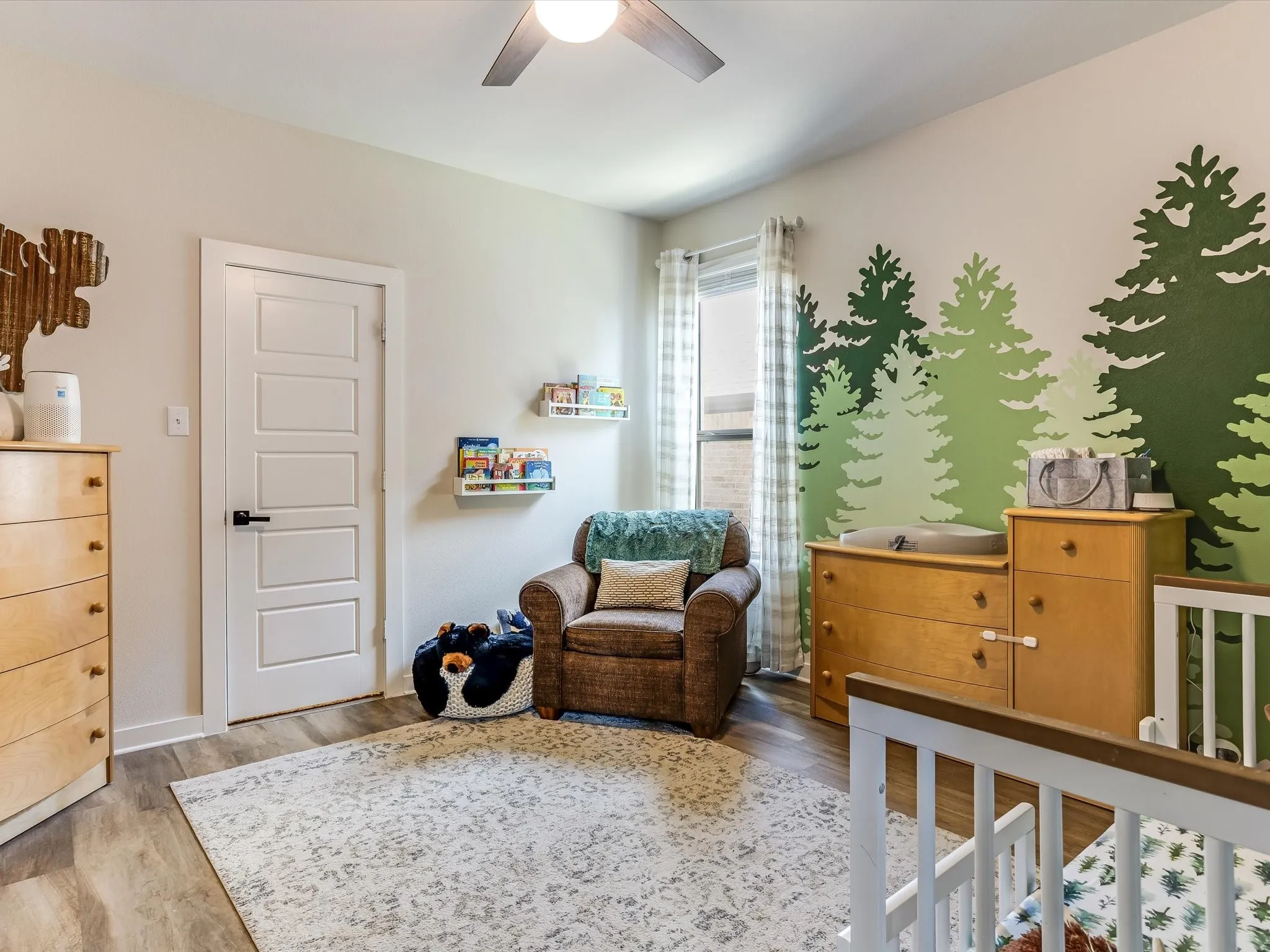 Room featuring a ceiling fan, wood-finish flooring, a window with curtains, and a five-panel interior door with matte black hardware