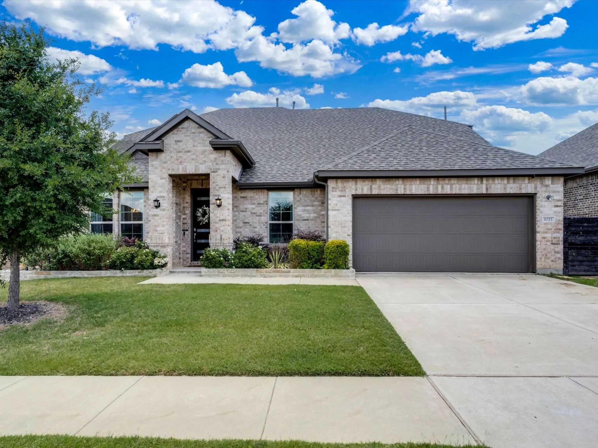 Brick veneer exterior with a dark gray shingle roof