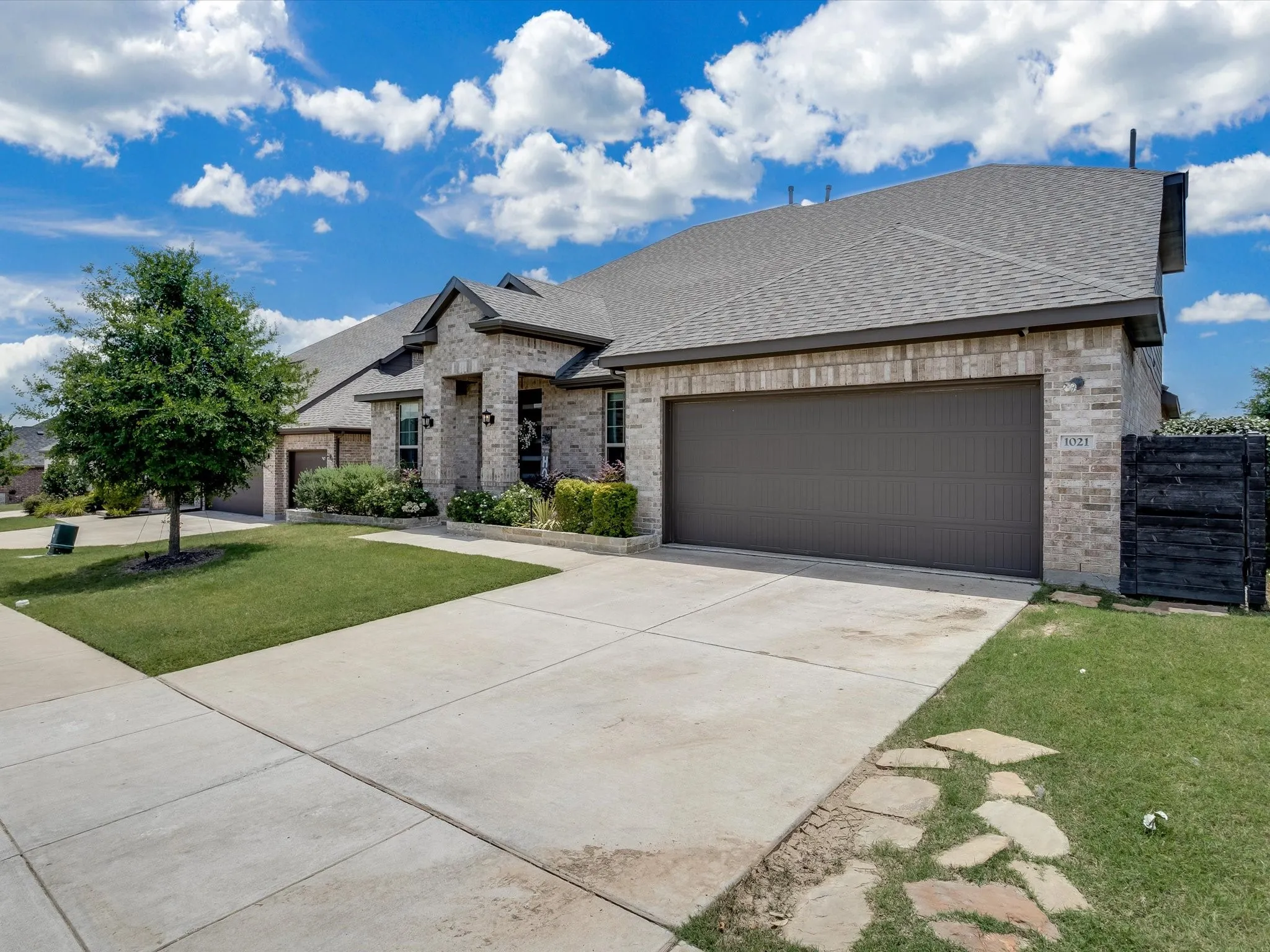 Brick exterior featuring a gabled roofline, an attached two-car garage, and a concrete driveway