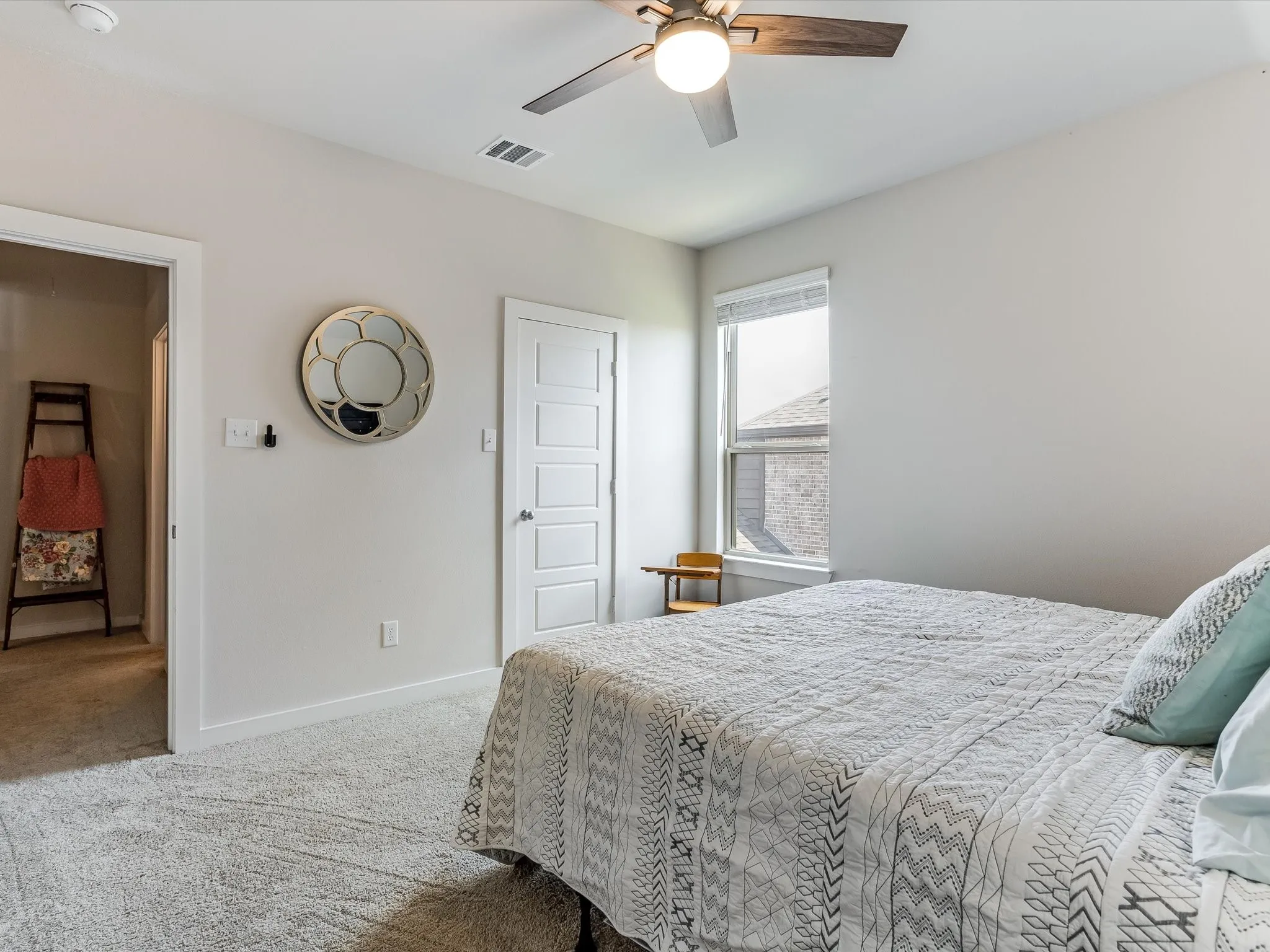 Carpeted interior space featuring a window with blinds, ceiling fan with integrated lighting, and a white paneled door