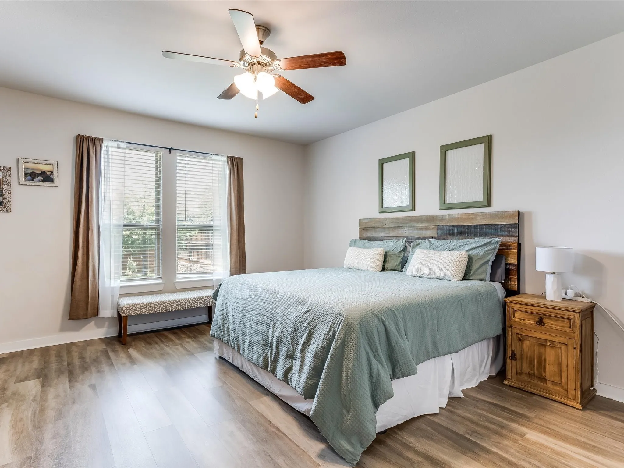 Bedroom featuring wood-finish flooring, a ceiling fan with integrated lighting, and a large window with blinds