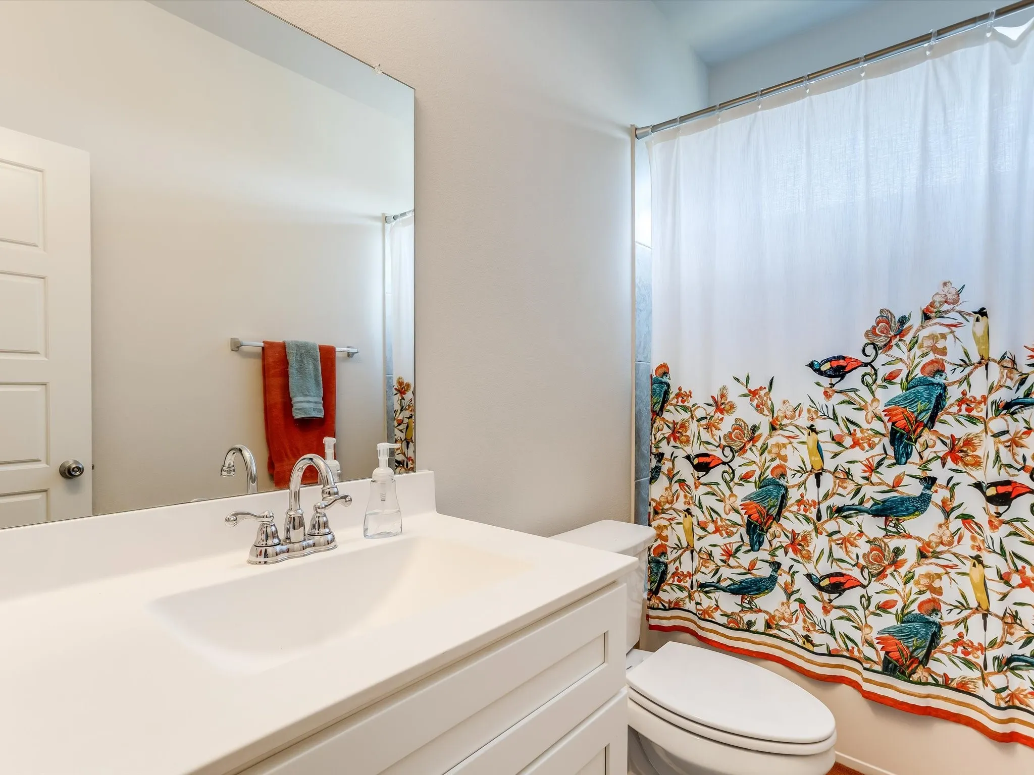 Bathroom featuring a white vanity with integrated sink, chrome faucet, and expansive wall mirror
