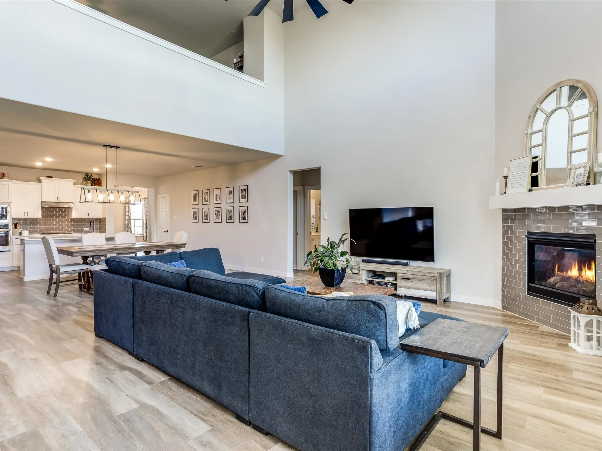 Vaulted ceiling living room featuring wood-finish flooring and a tiled fireplace