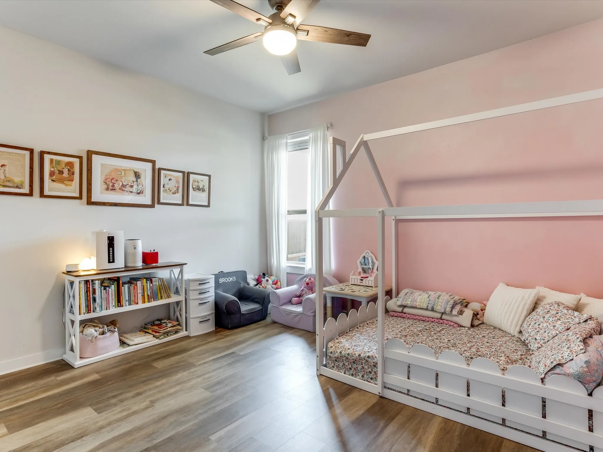 Spacious room featuring wood-finish flooring, a contemporary ceiling fan with light fixture, and a large window with white blinds