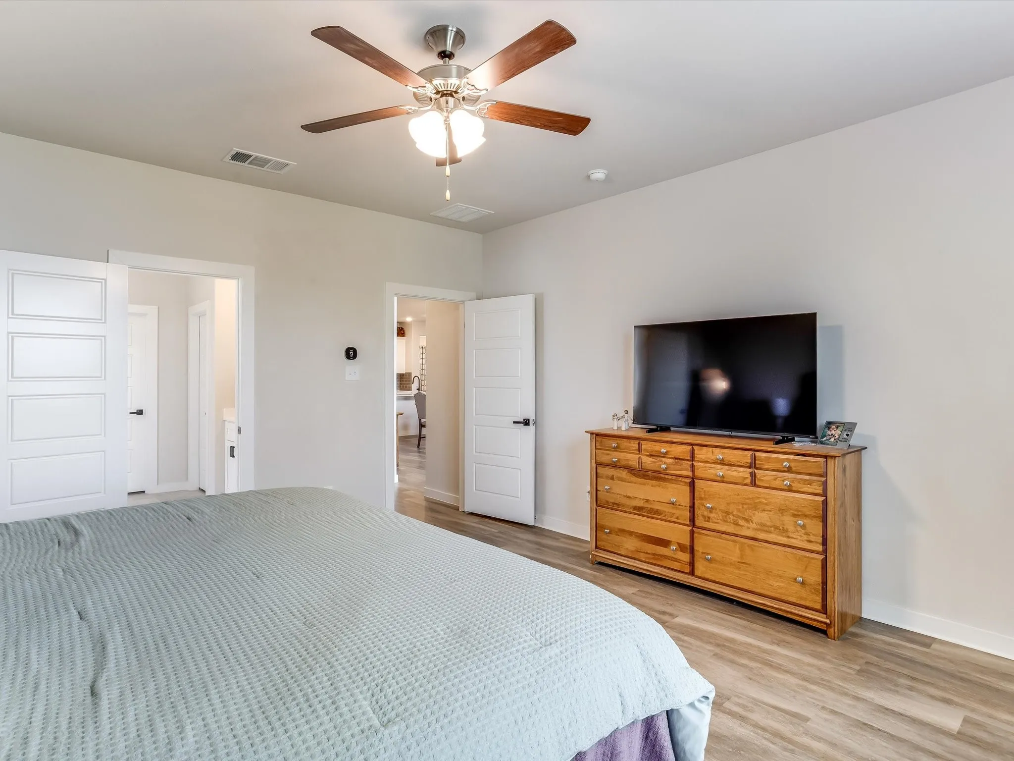 Bedroom featuring wood-finish flooring, a ceiling fan with integrated lighting, and two panel doors