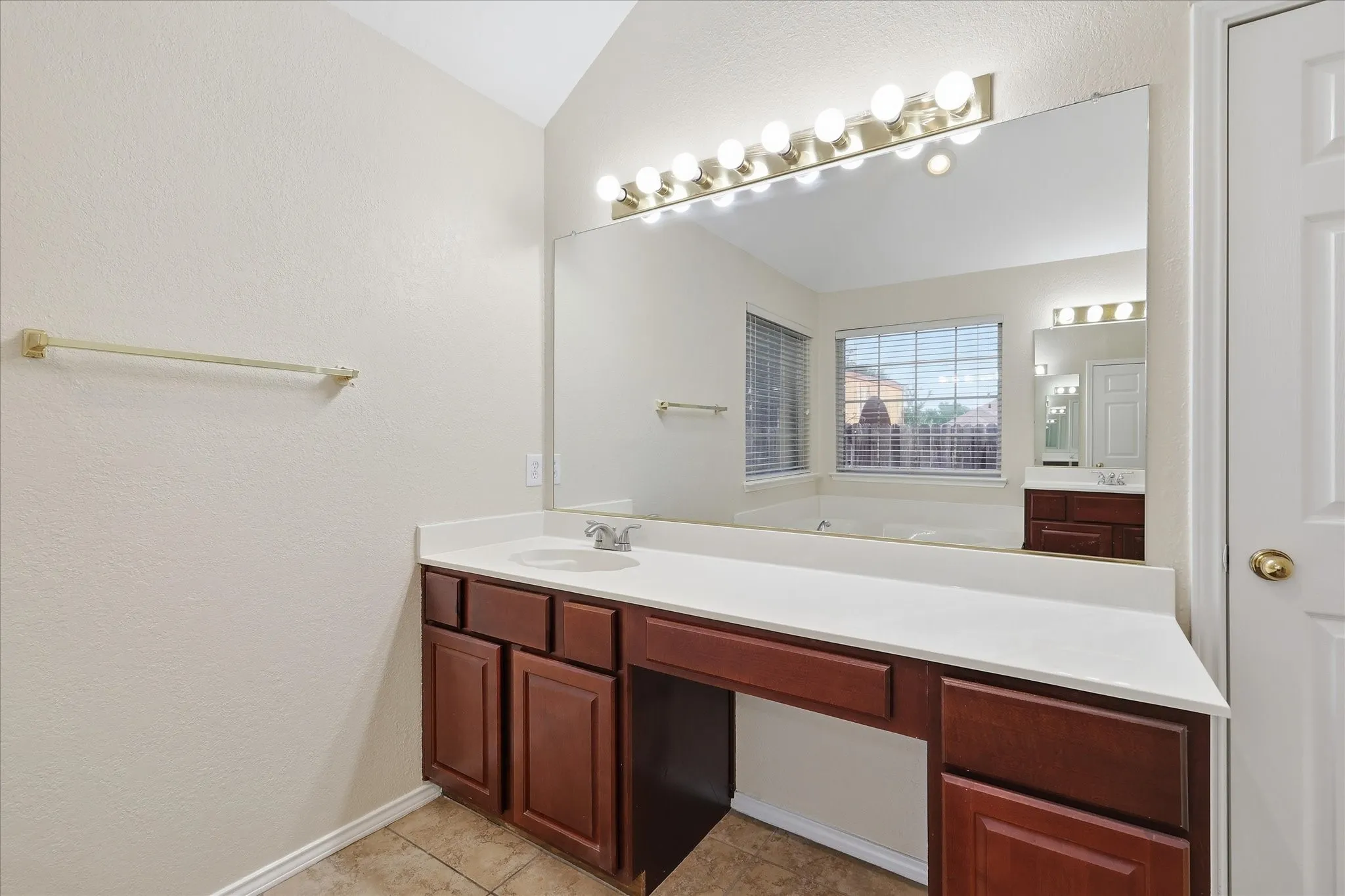 Double vanity with integrated sinks and white countertops, featuring wood-finish cabinetry