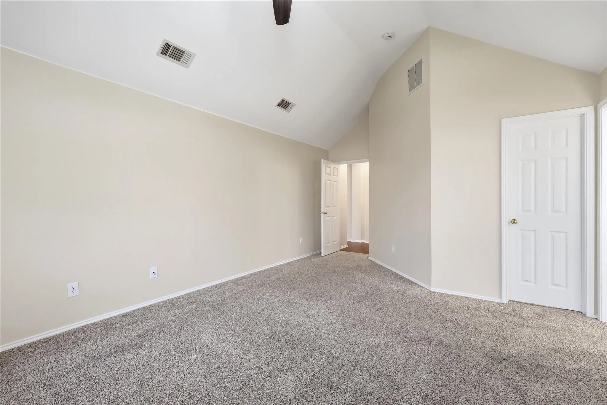 Spacious room featuring vaulted ceilings, neutral-toned walls, and plush carpet flooring