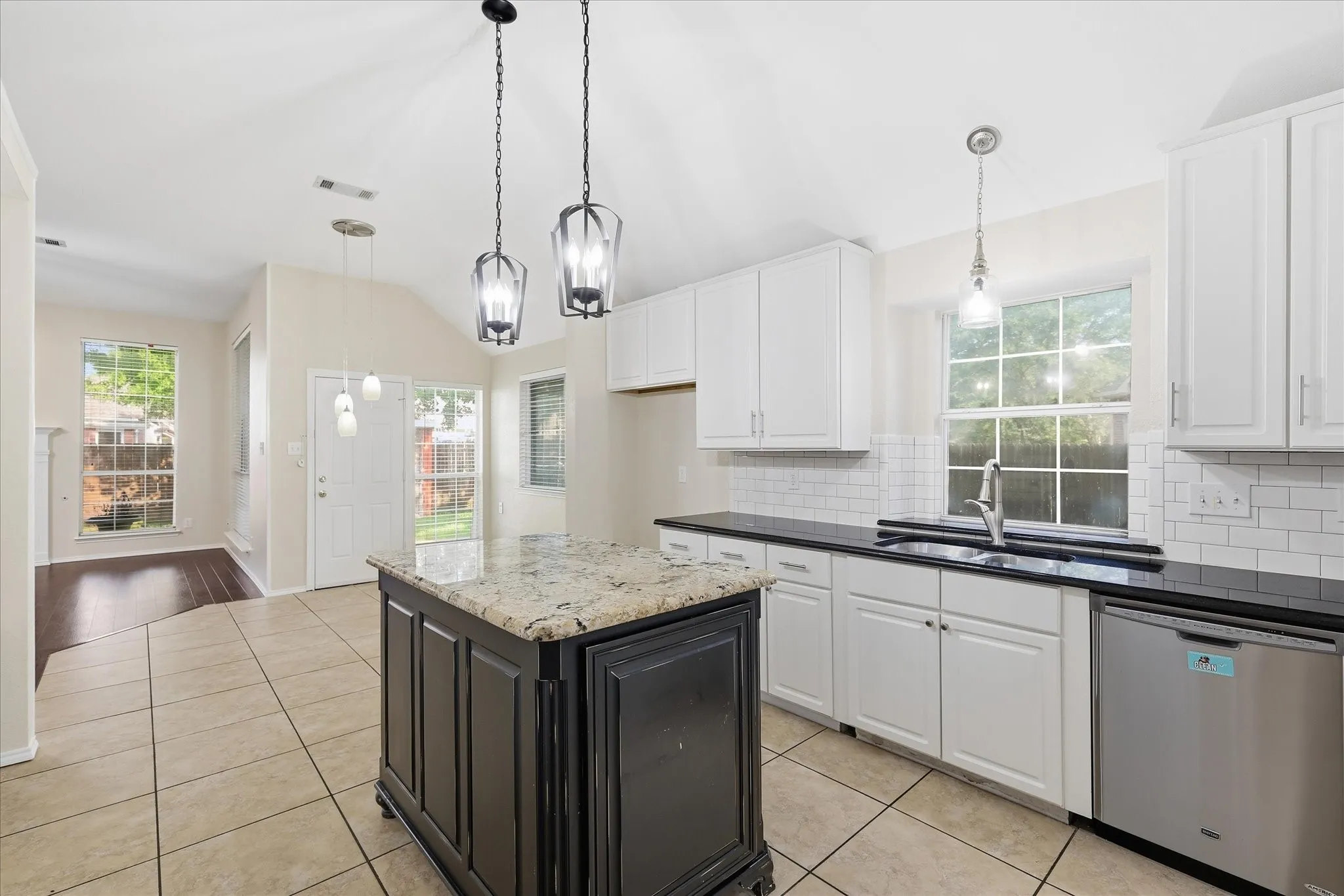 Kitchen featuring a center island with a granite countertop, white cabinetry, dark countertops, subway tile backsplash, and stainless steel appliances