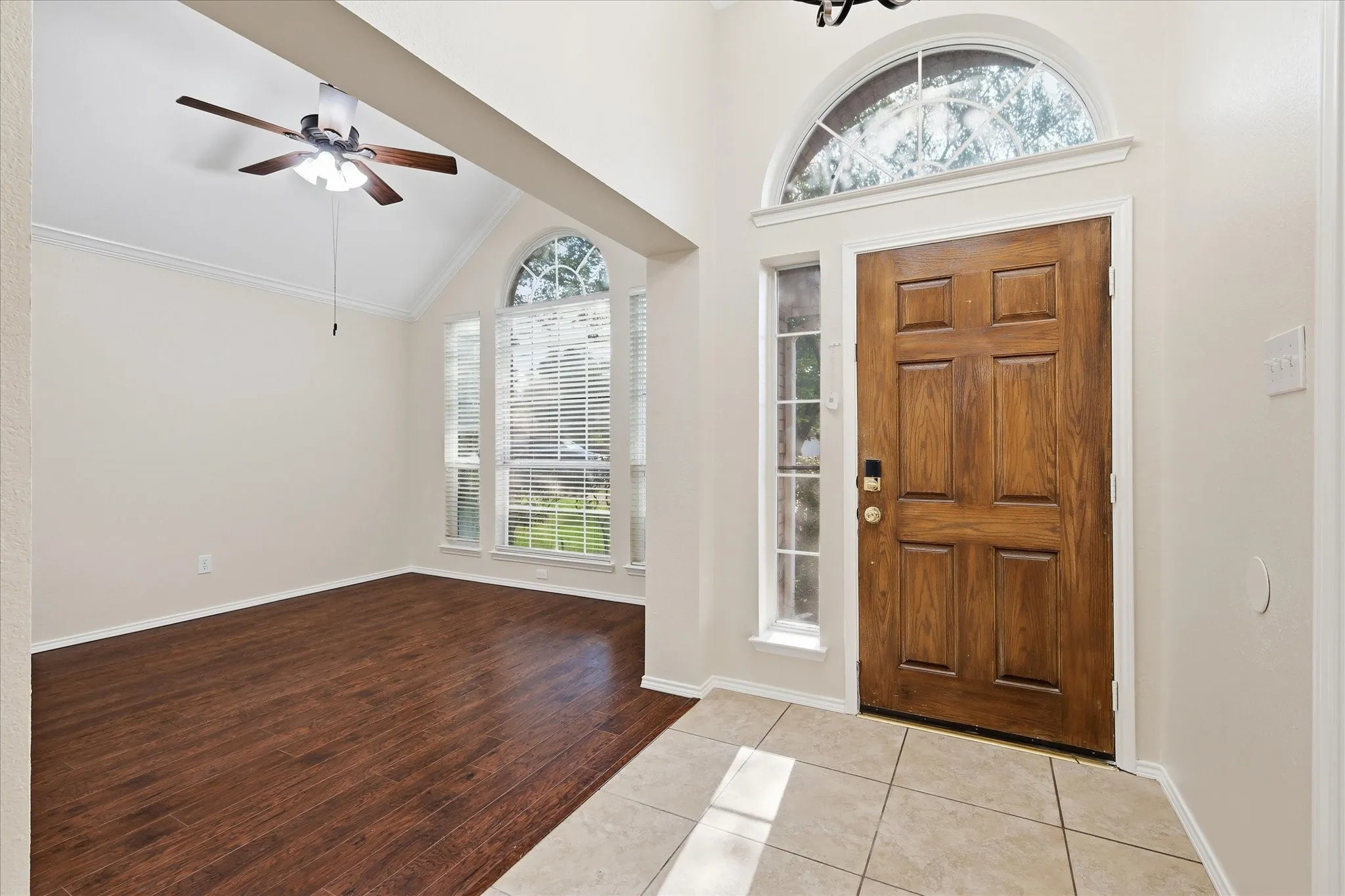 Entryway featuring a paneled wood door with an arched transom window, side-light windows, and a tiled floor