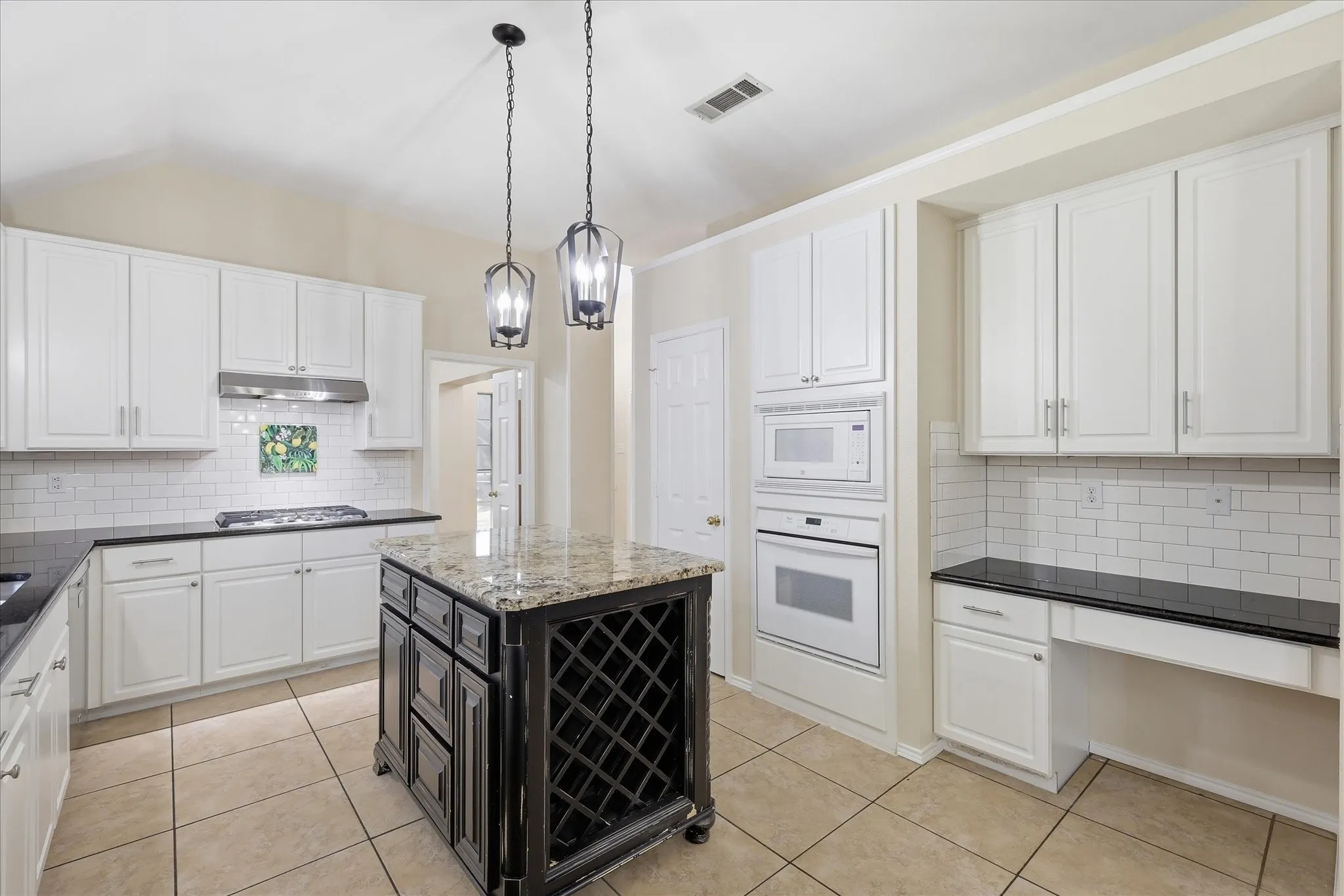 Kitchen featuring a central island with wine storage, granite countertops, and two pendant light fixtures
