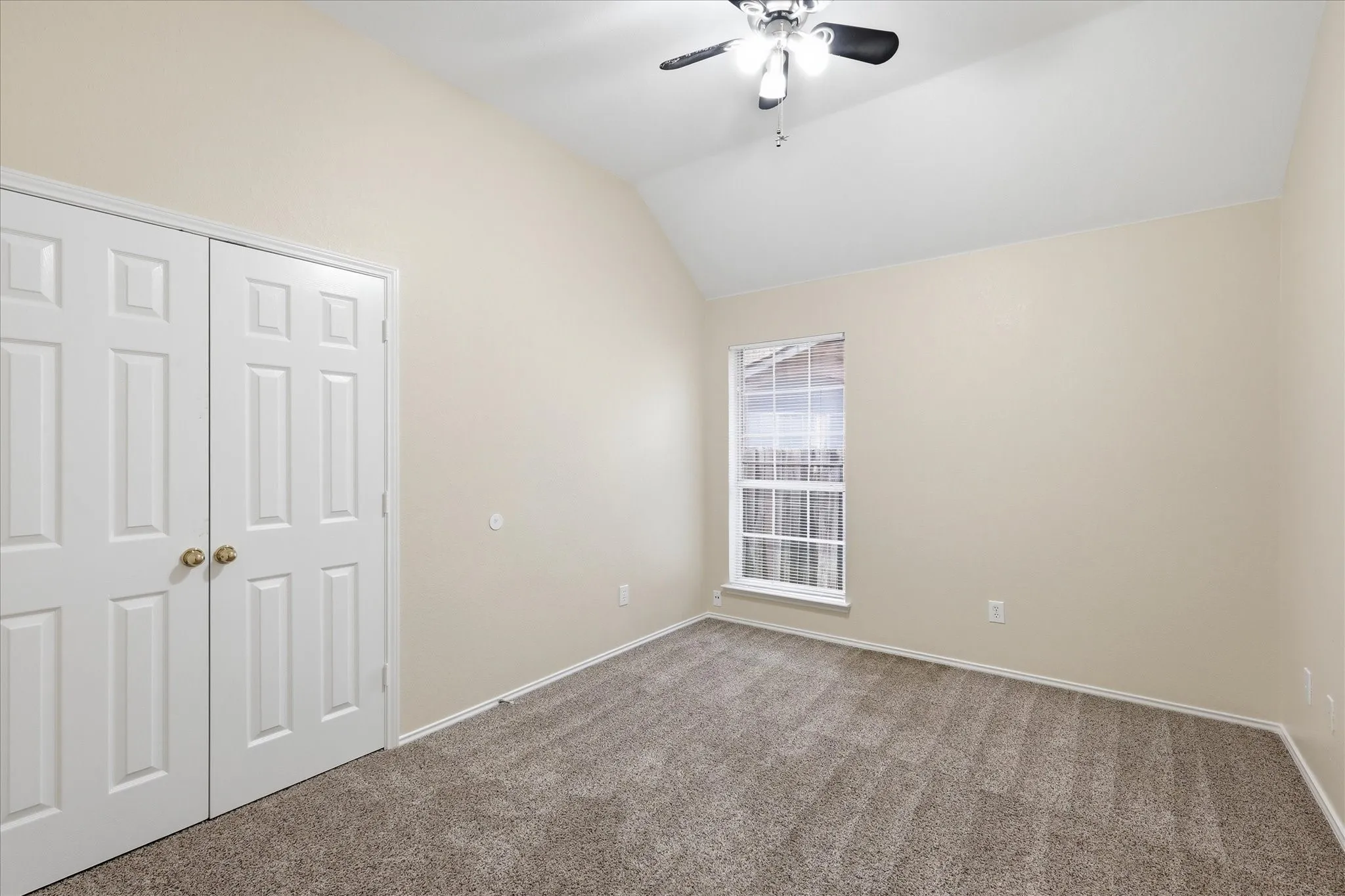 Carpeted room featuring a vaulted ceiling and a ceiling fan