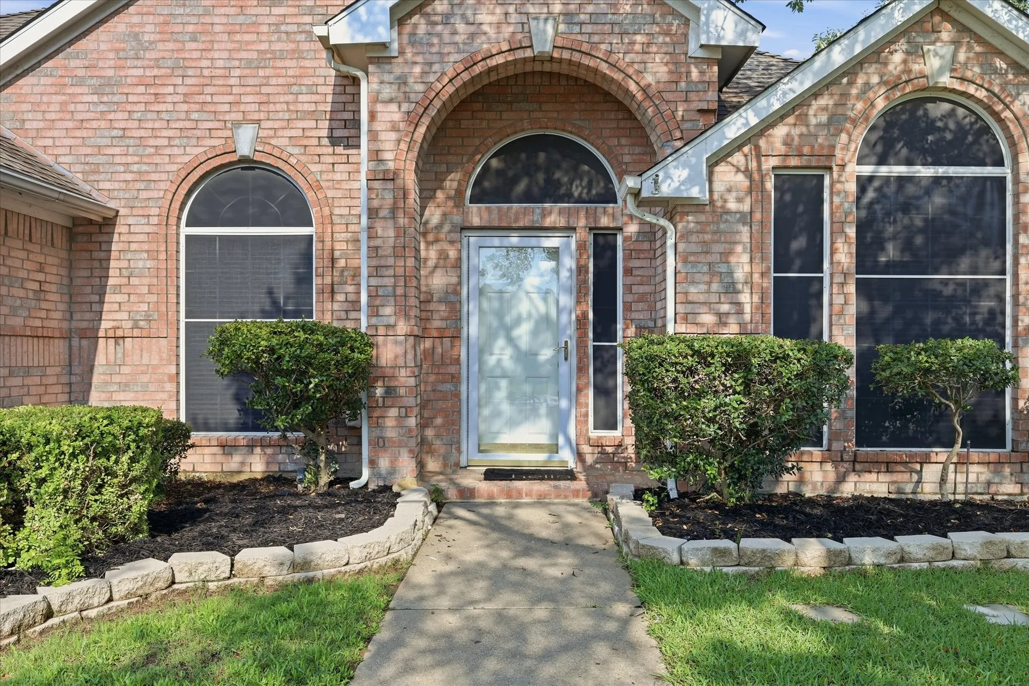 Brick exterior featuring arched windows and a prominent entry