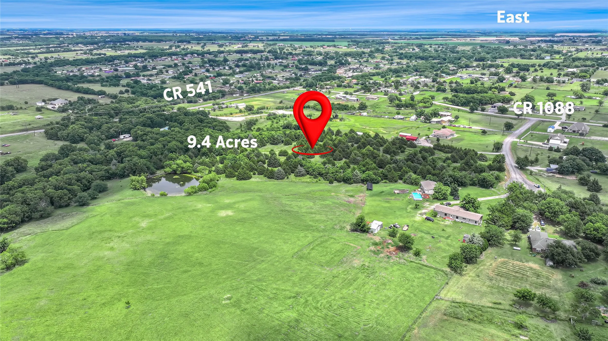 Expansive 9.4-acre property featuring a mix of open green fields and mature trees