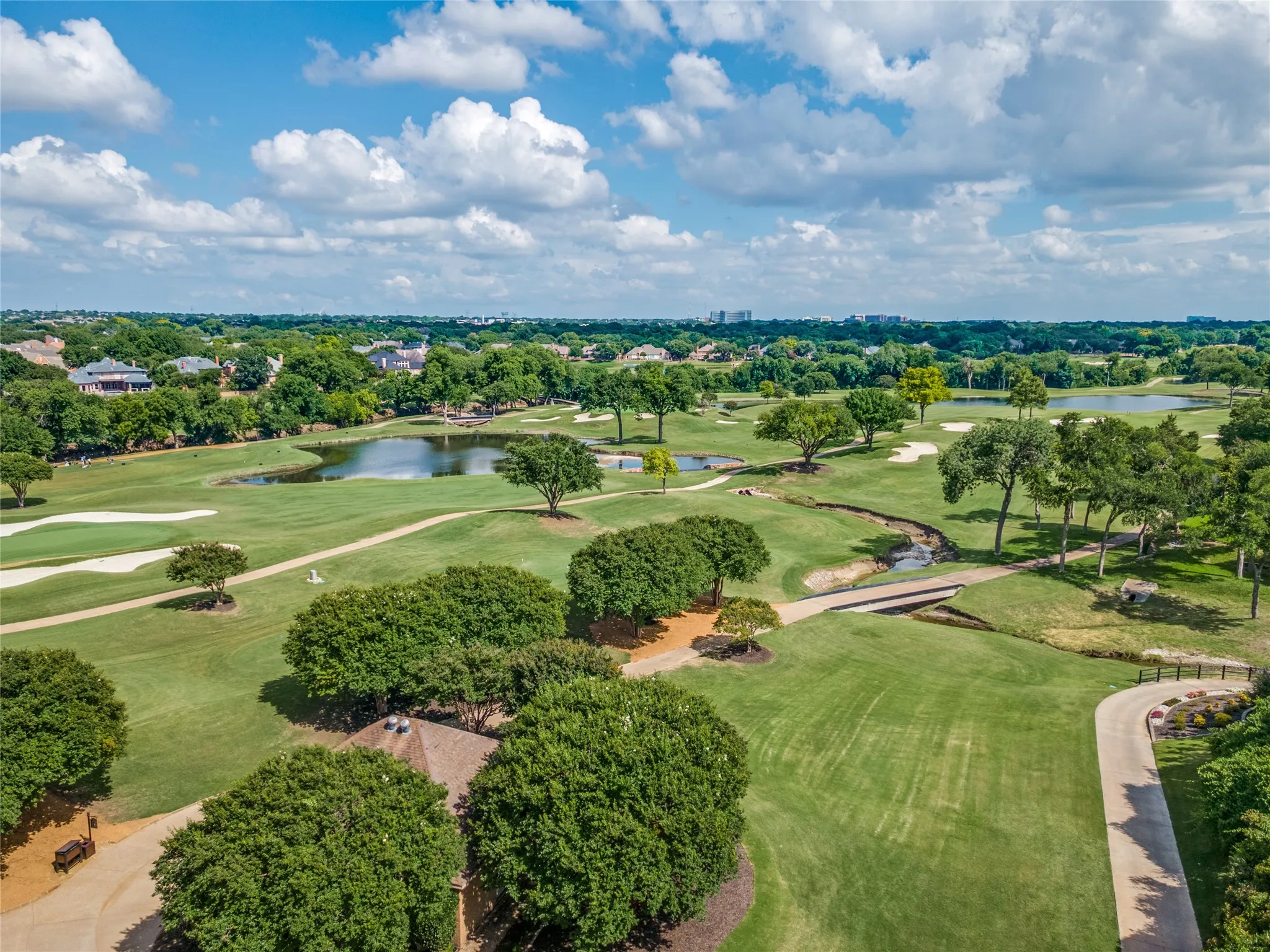 Expansive golf course landscape featuring lush green fairways, multiple water features, and mature trees
