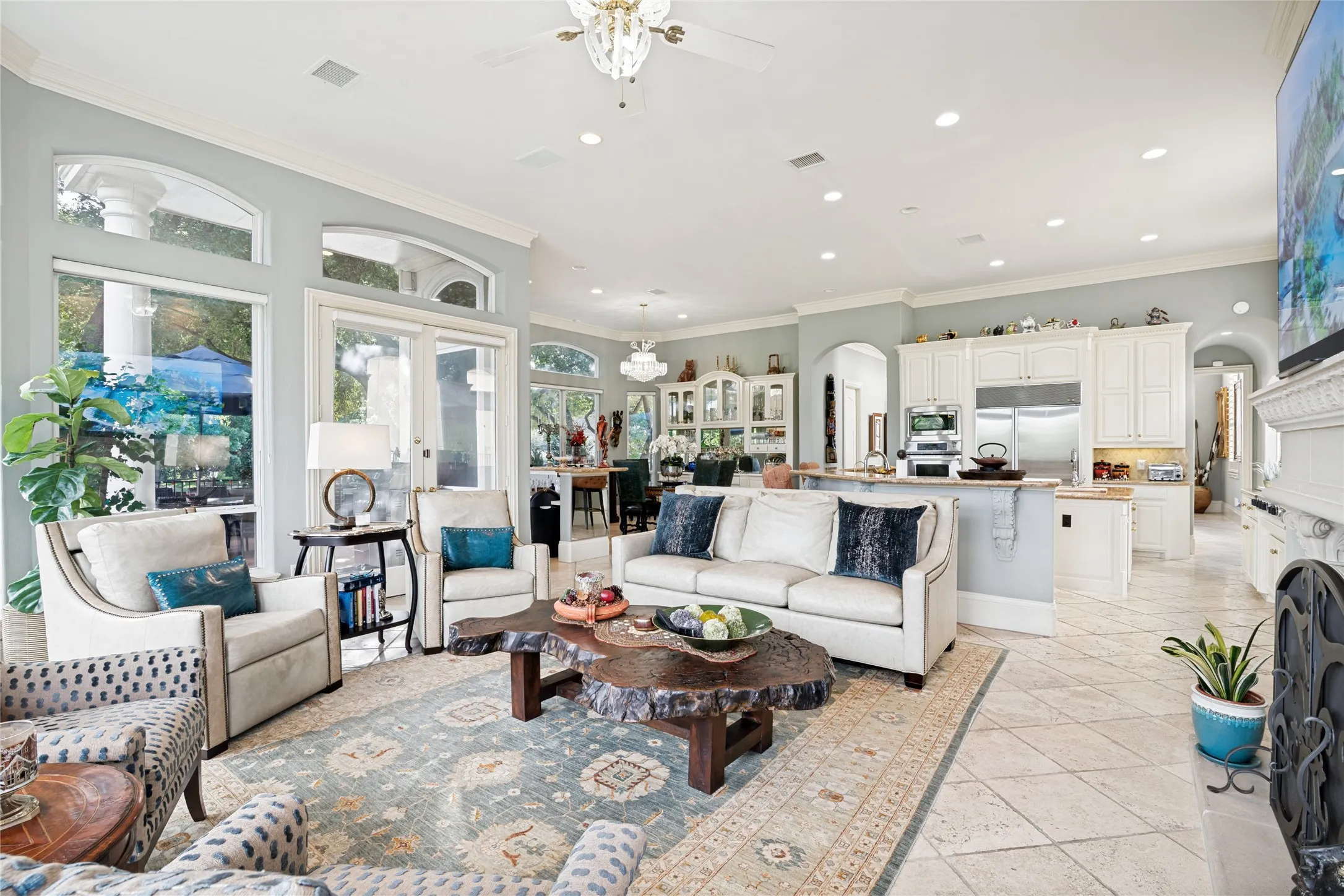Open-concept living area featuring a fireplace with ornate mantel, recessed lighting, and crown molding