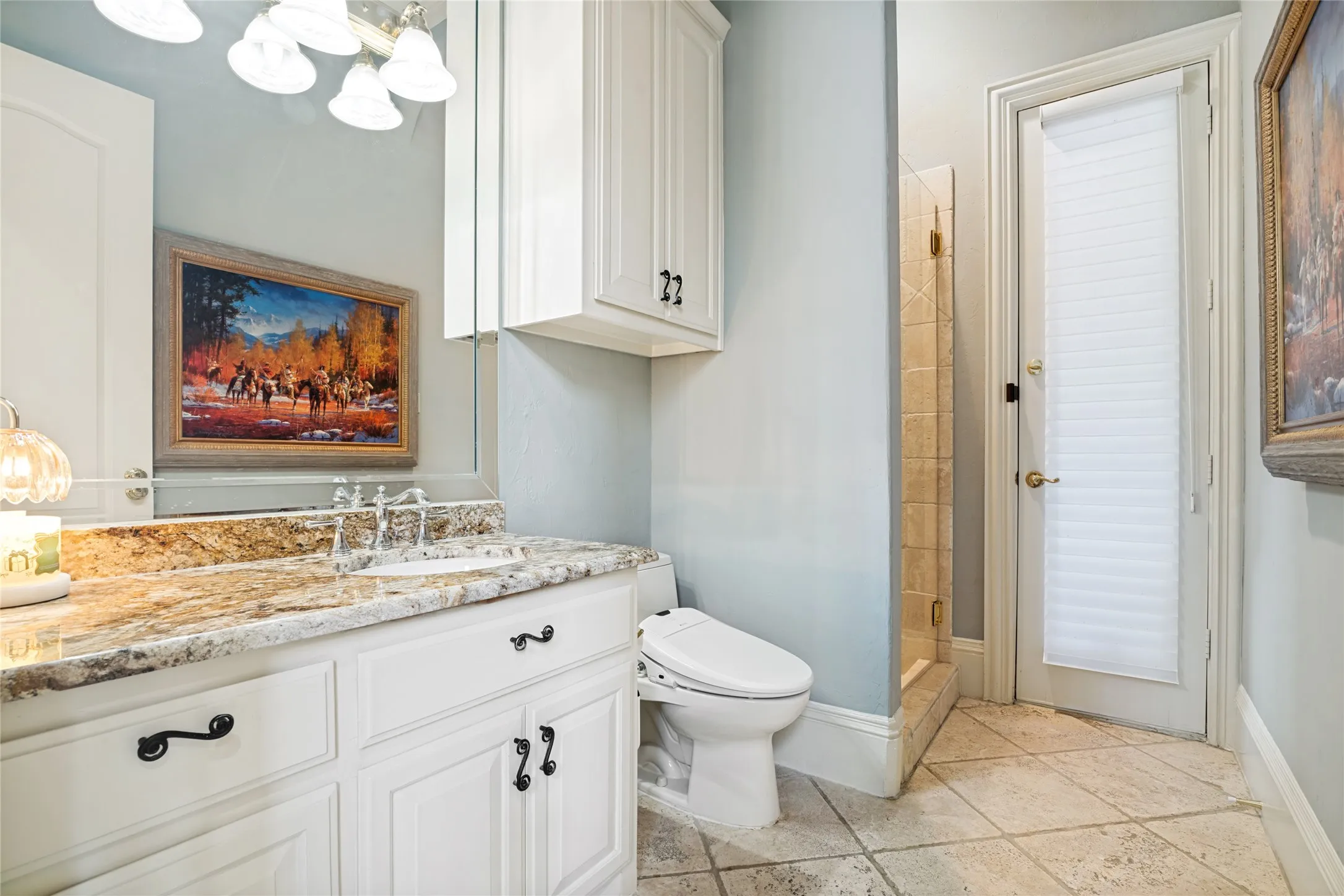 Bathroom vanity with a polished stone countertop, undermount sink, and wall-mounted mirror