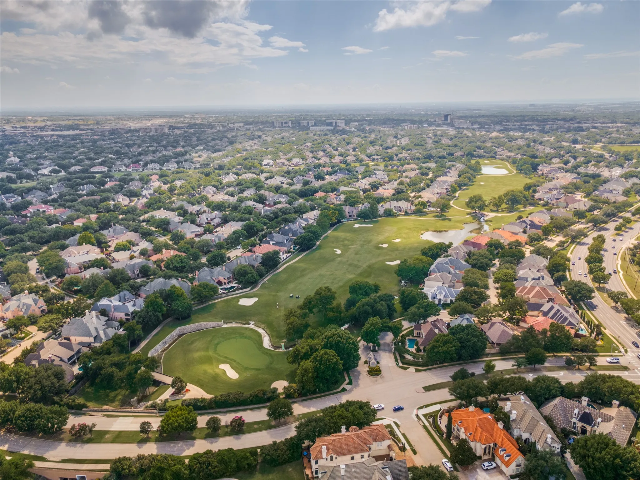 Expansive residential area featuring a golf course, numerous homes with varied architectural styles, mature trees, and well-maintained roadways
