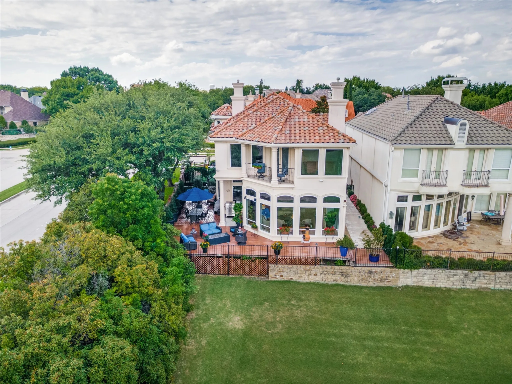 The deck wraps around the side and back of the house, green grass maintained my golf course.
