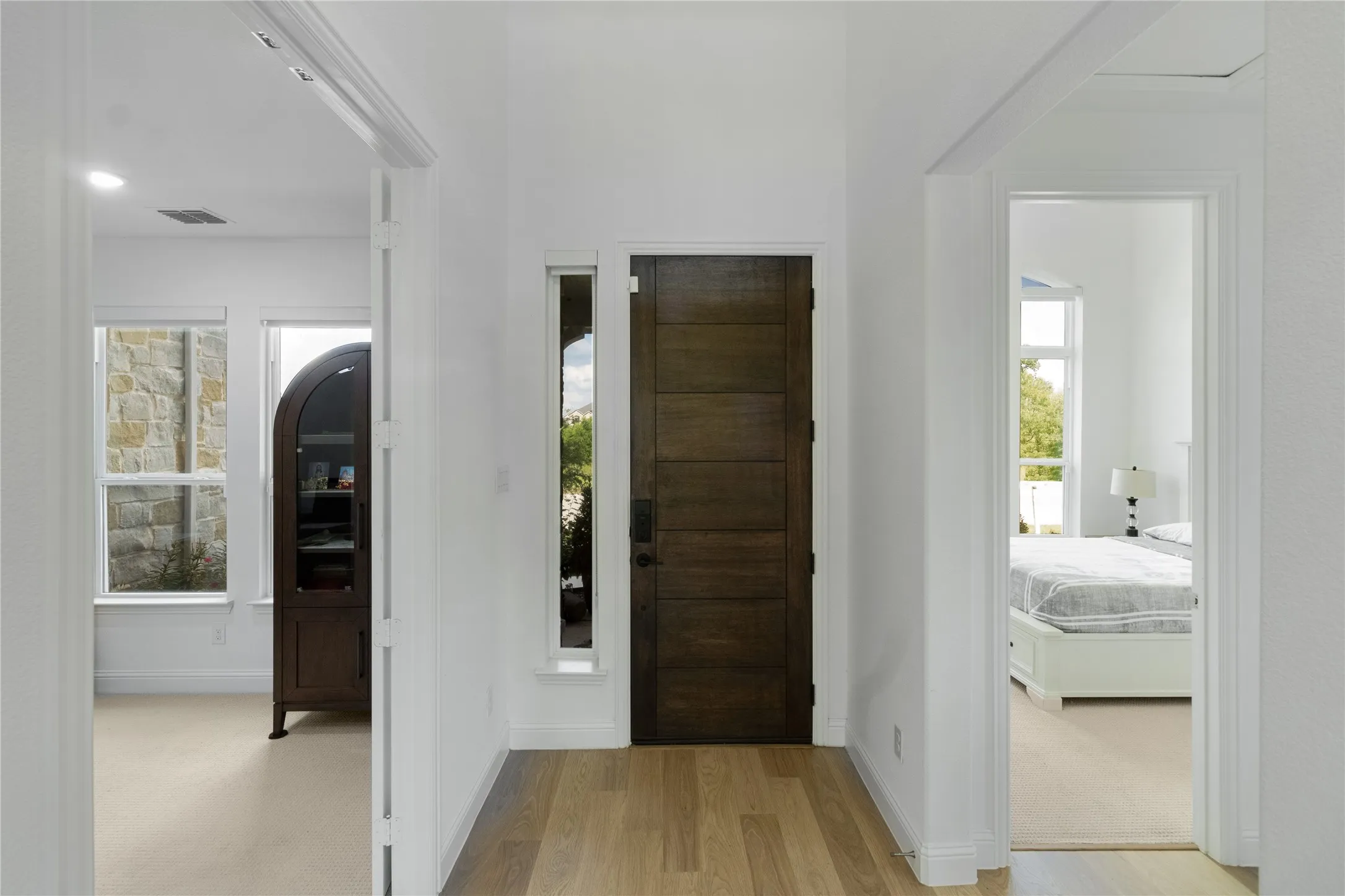 Entryway featuring a solid wood-finish door with sidelight, light wood-finish flooring, and white walls
